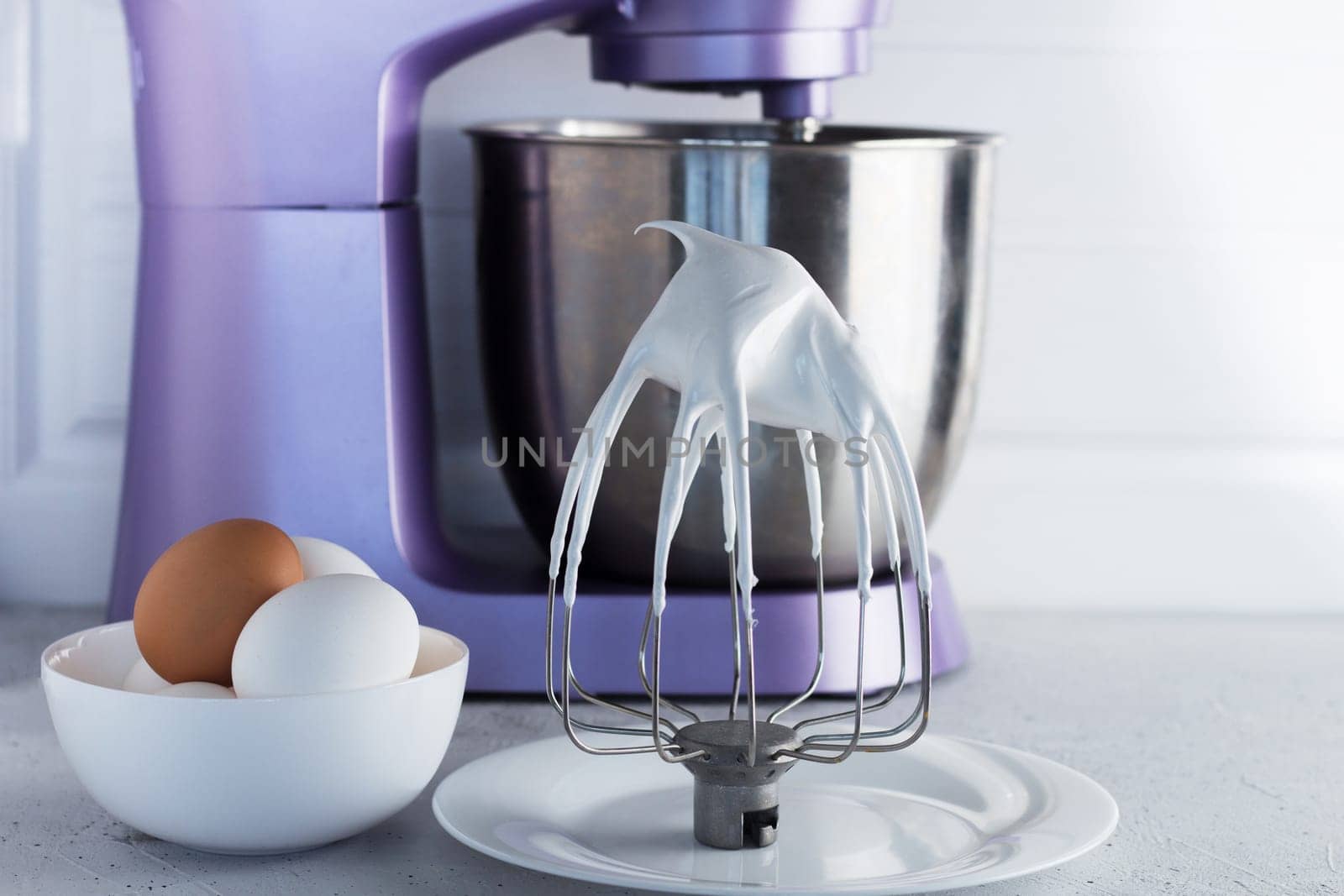 Modern mixer on the kitchen table with eggs and whipped meringue.