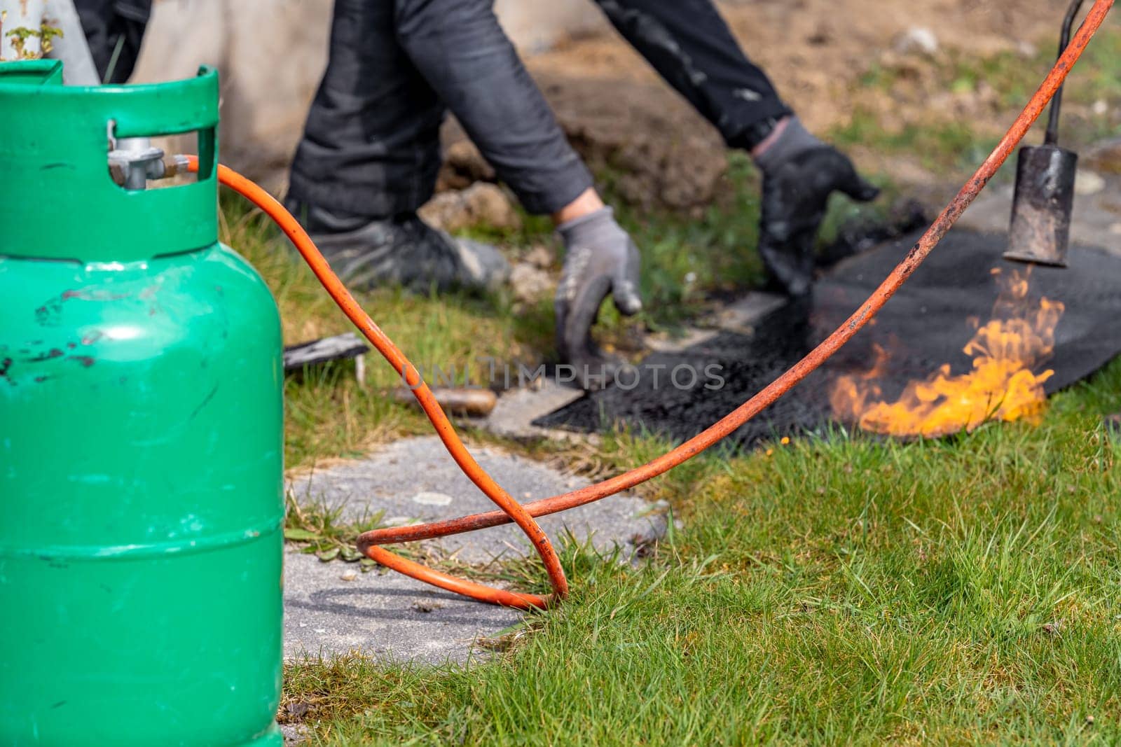 heating asphalt belts for waterproofing the foundation of the house with the help of a gas tank and an open fire by Edophoto