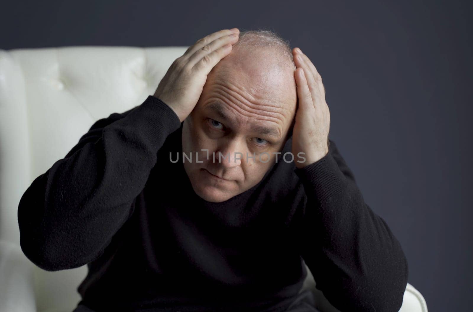 The man is concerned about the problem of hair loss and baldness. He examines his hair on his head.