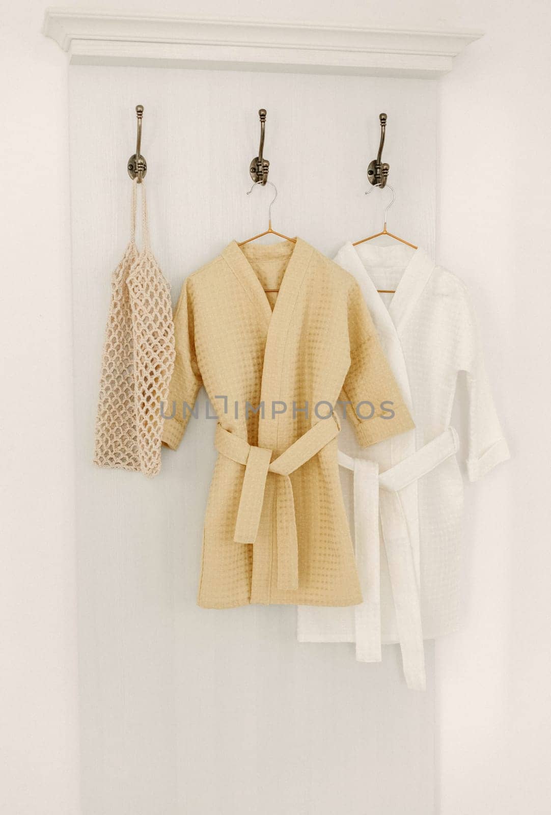 Linen bathrobes hang on a hanger in the bathroom.