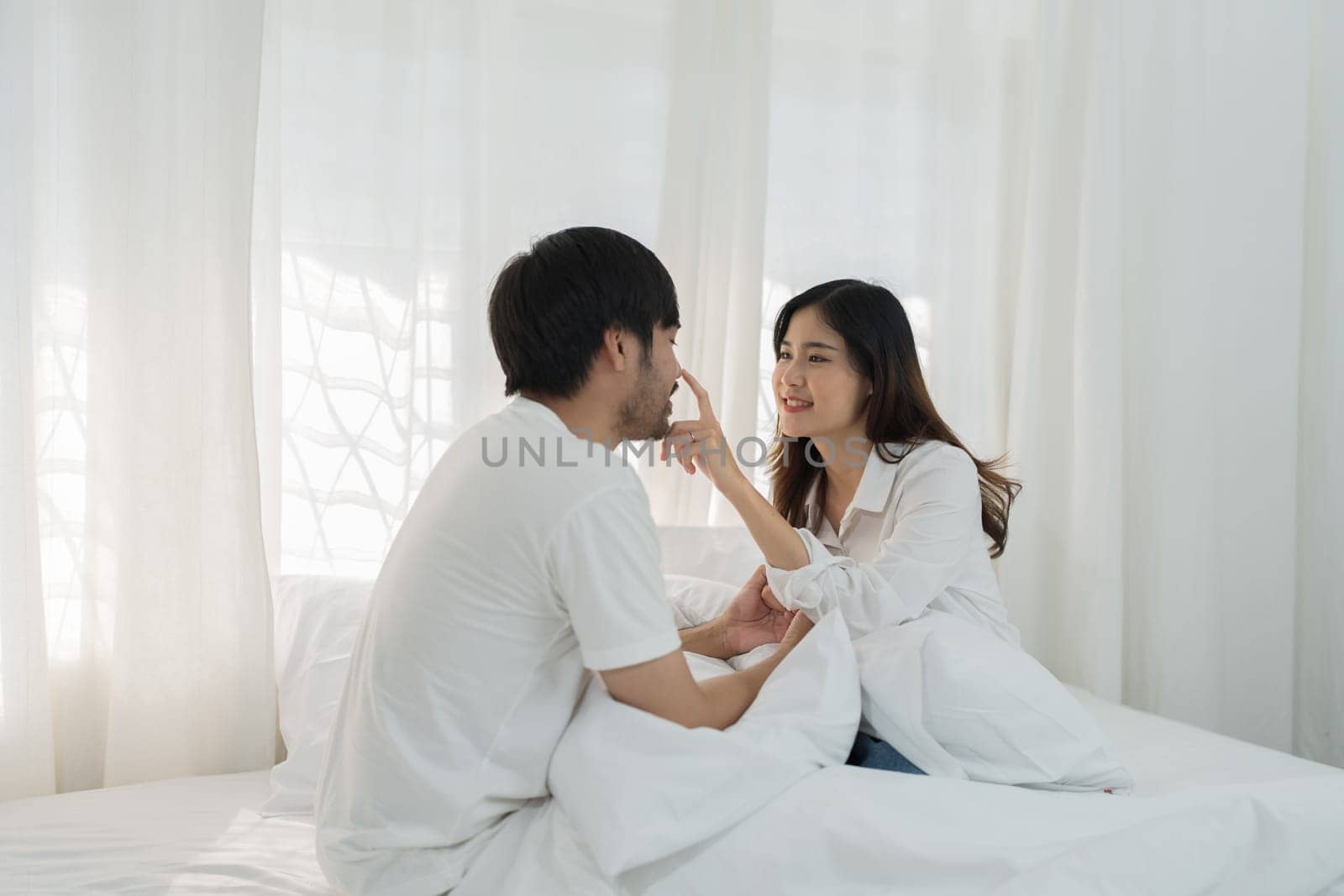 Asian Romantic couple in bed enjoying sensual foreplay Happy sensual young couple lying in bed together. Beautiful loving couple kissing in bed