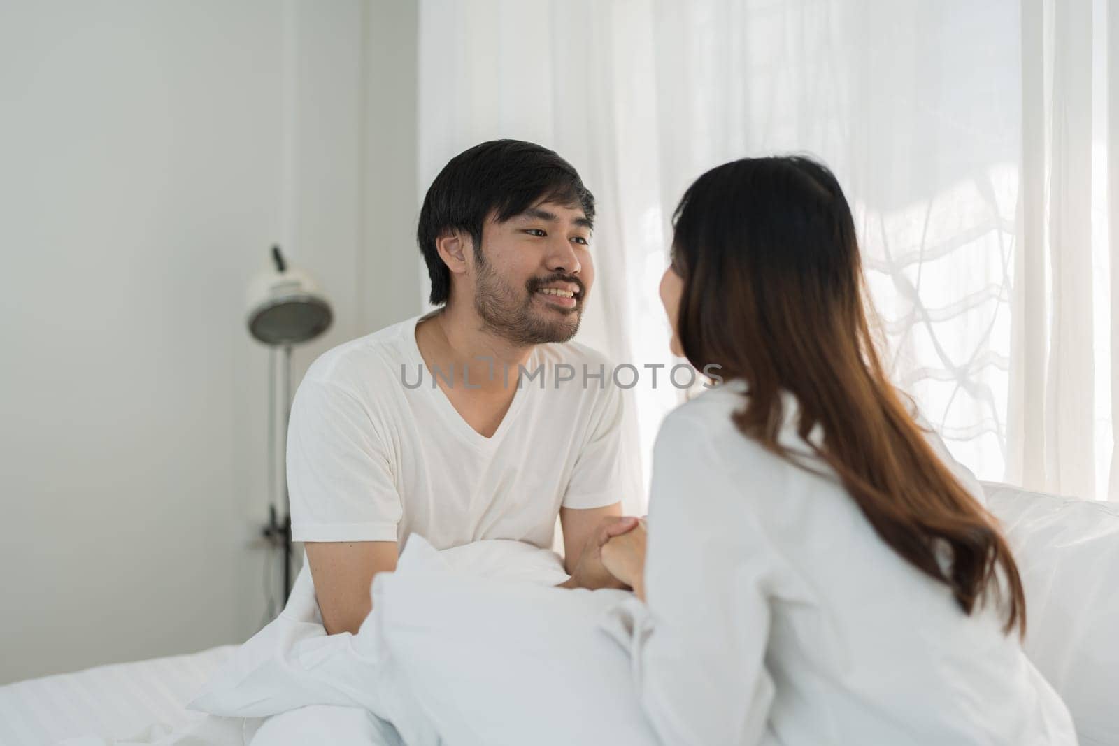 Asian Romantic couple in bed enjoying sensual foreplay Happy sensual young couple lying in bed together. Beautiful loving couple kissing in bed