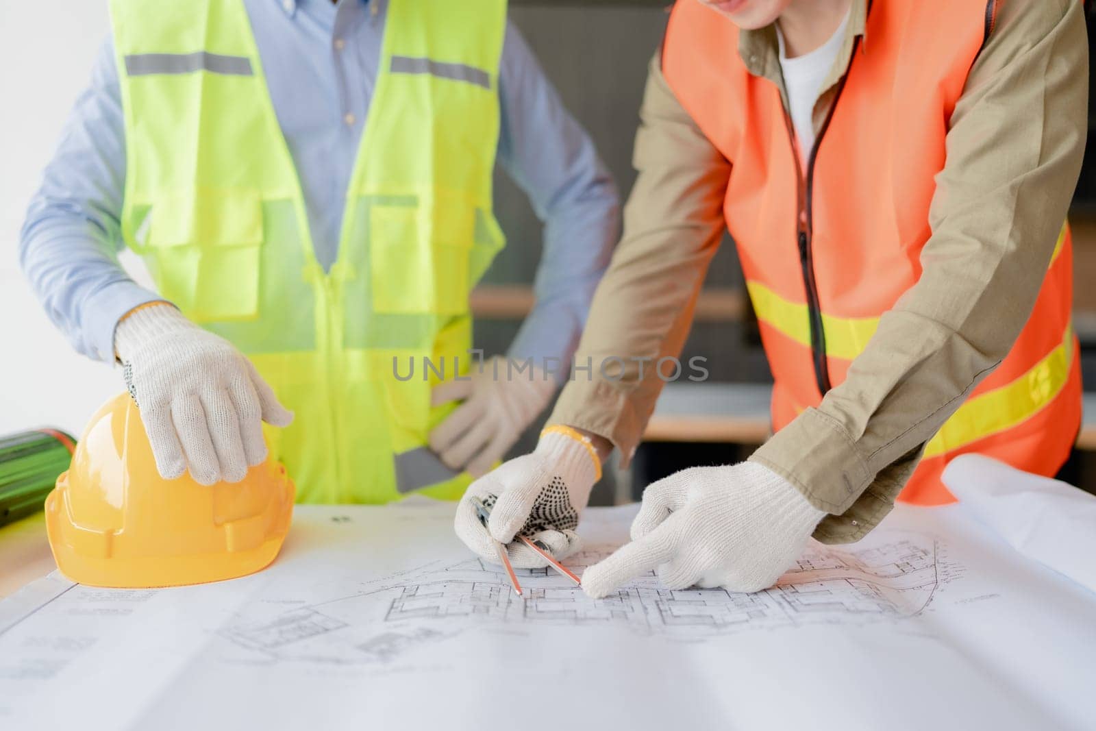 multi ethnic engineer brainstorming and measuring for cost estimating on paperworks and floor plan drawings about design architectural and engineering for houses and buildings.