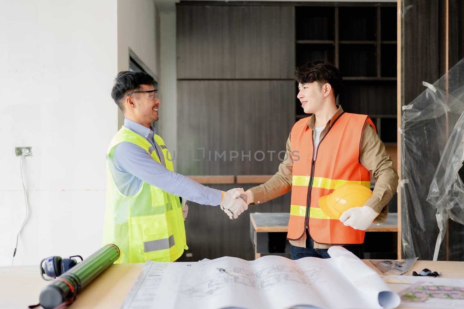 multi ethnic engineer brainstorming with deal and measuring for cost estimating on paperworks and floor plan drawings, contract and agreement concepts by Manastrong