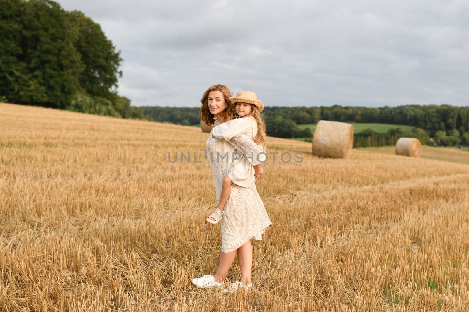 Mother holds daughter in her arms in a field with wheat Mothers day