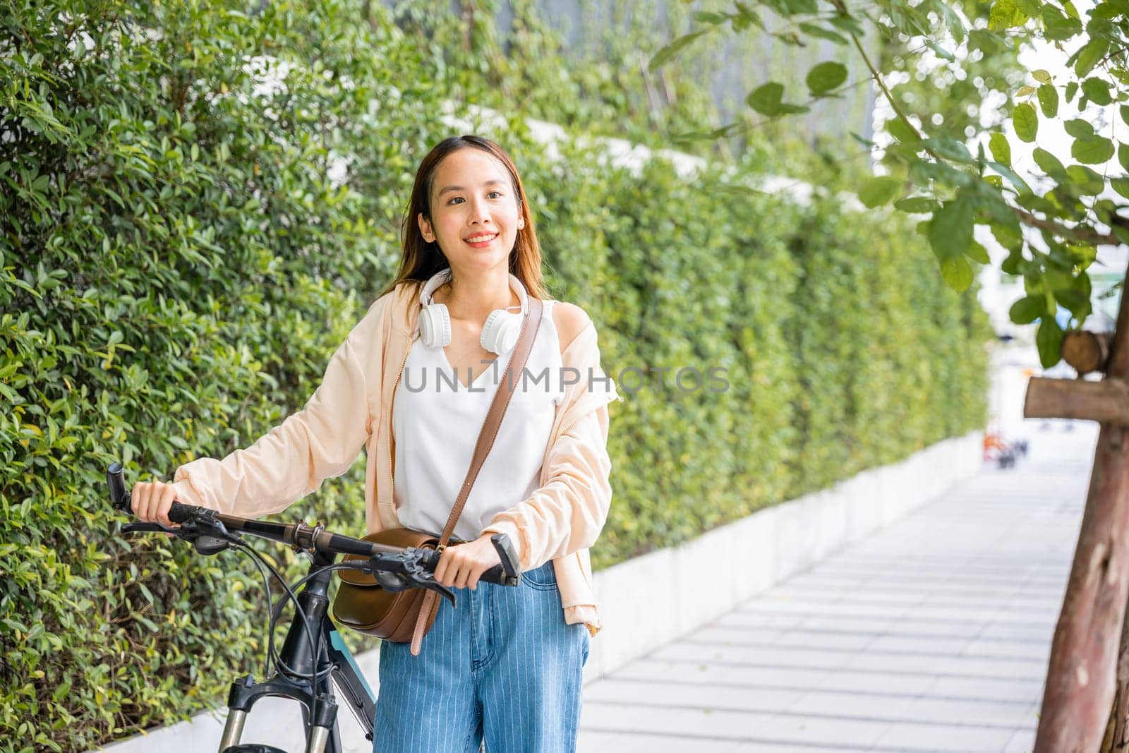 Happy female smiling walk down the street with her bike on city road by Sorapop