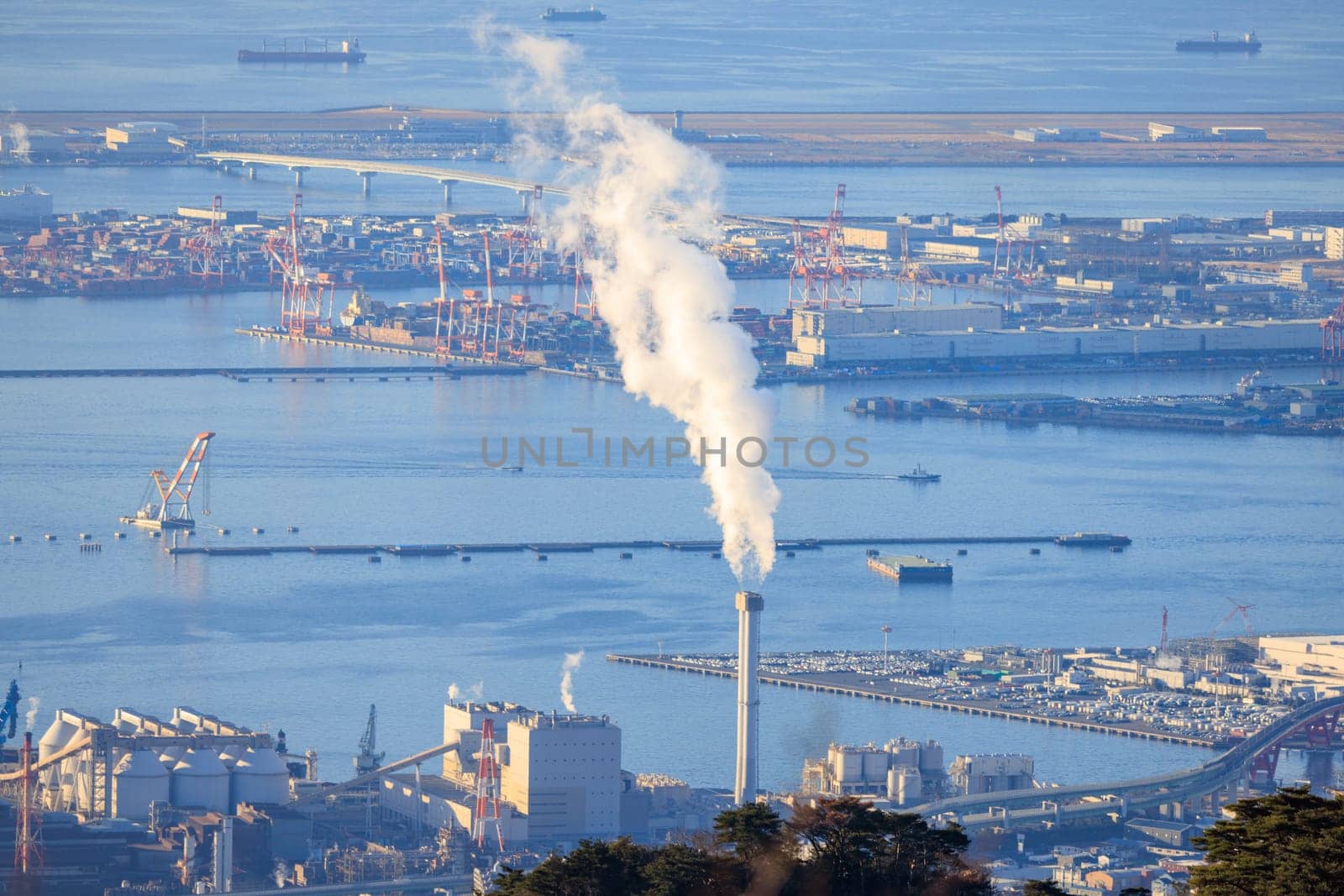 Smoke from chimney and loading cranes at empty industrial port. High quality photo