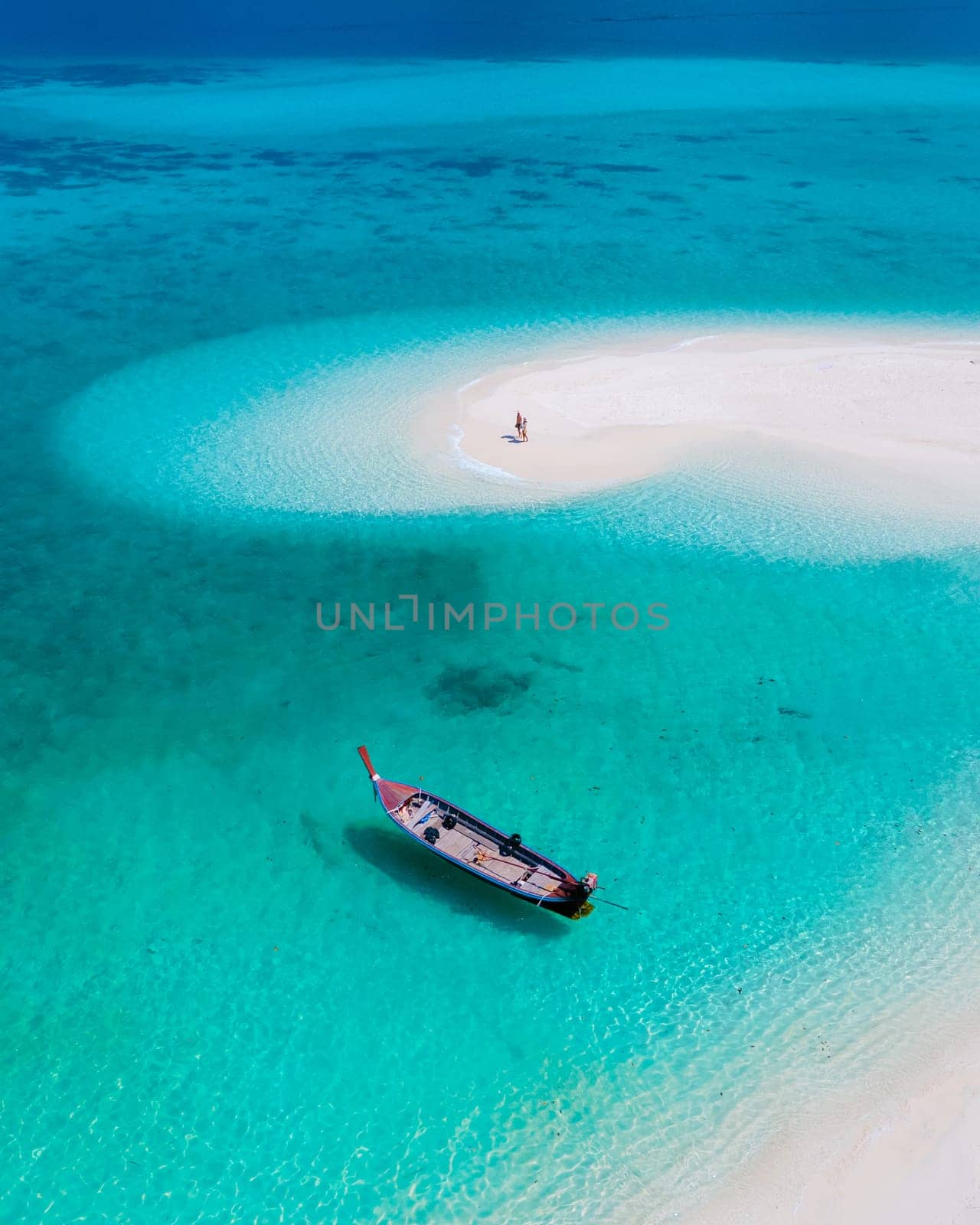 couple of men and women on the beach of Ko Lipe Island Thailand. drone aerial view of a sandbank in the ocean on a sunny day