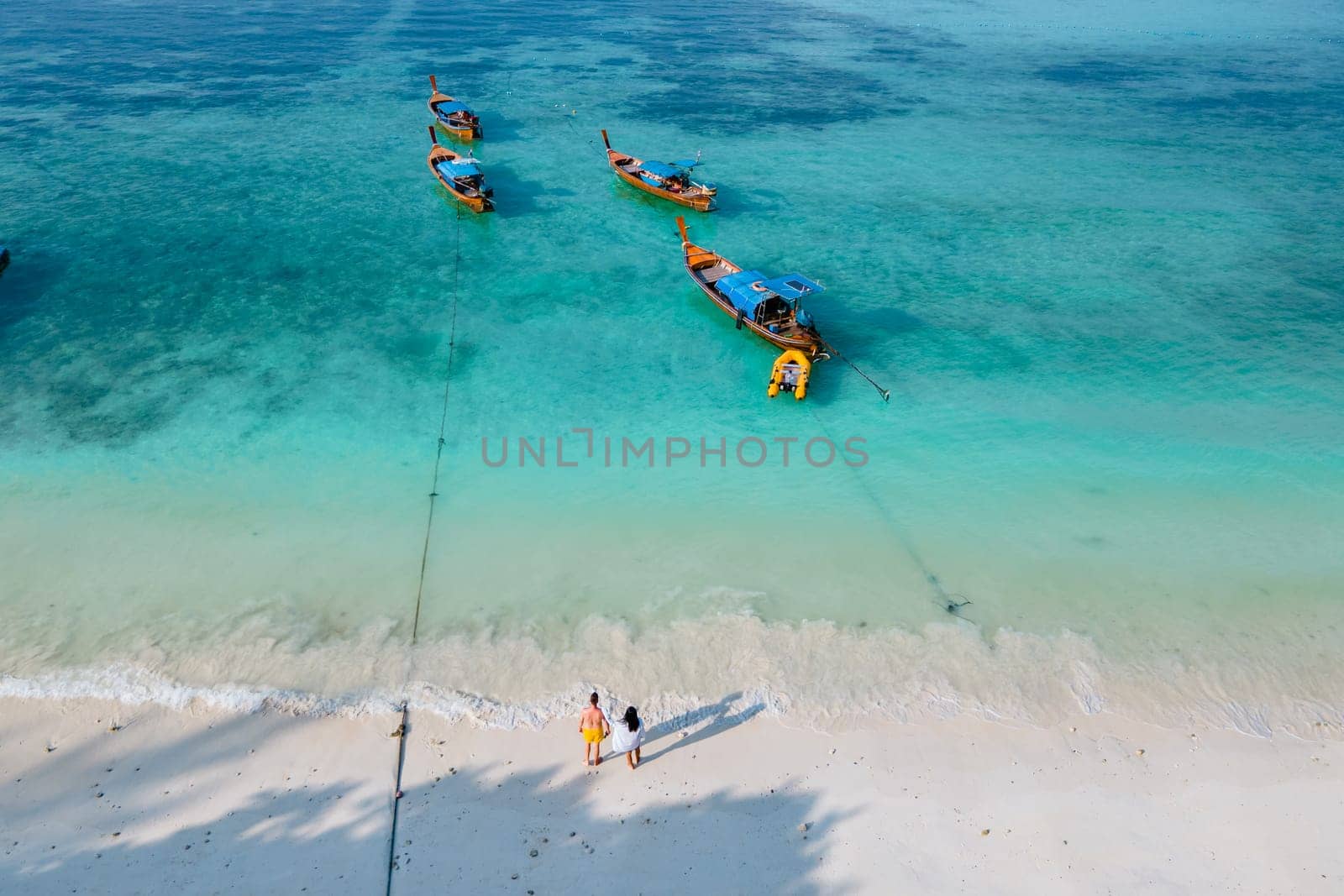 couple of men and women on the beach of Ko Lipe Island Thailand. drone aerial view of a sandbank in the ocean