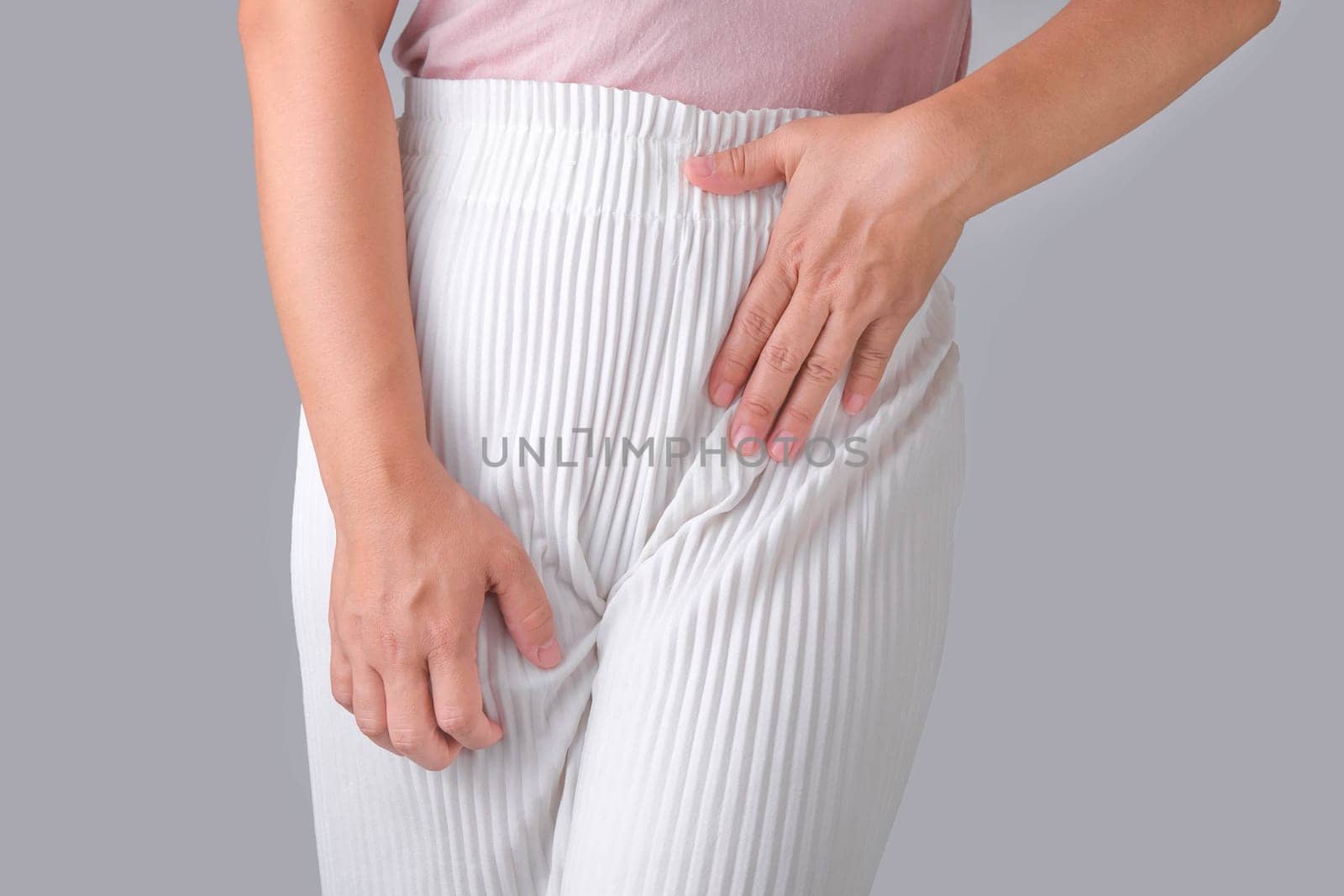 Woman with hands on her crotch isolated on white background. Female hand holding her crotch with pelvic pain or vaginal itching. gynecological problems. Health hygiene concept by TEERASAK