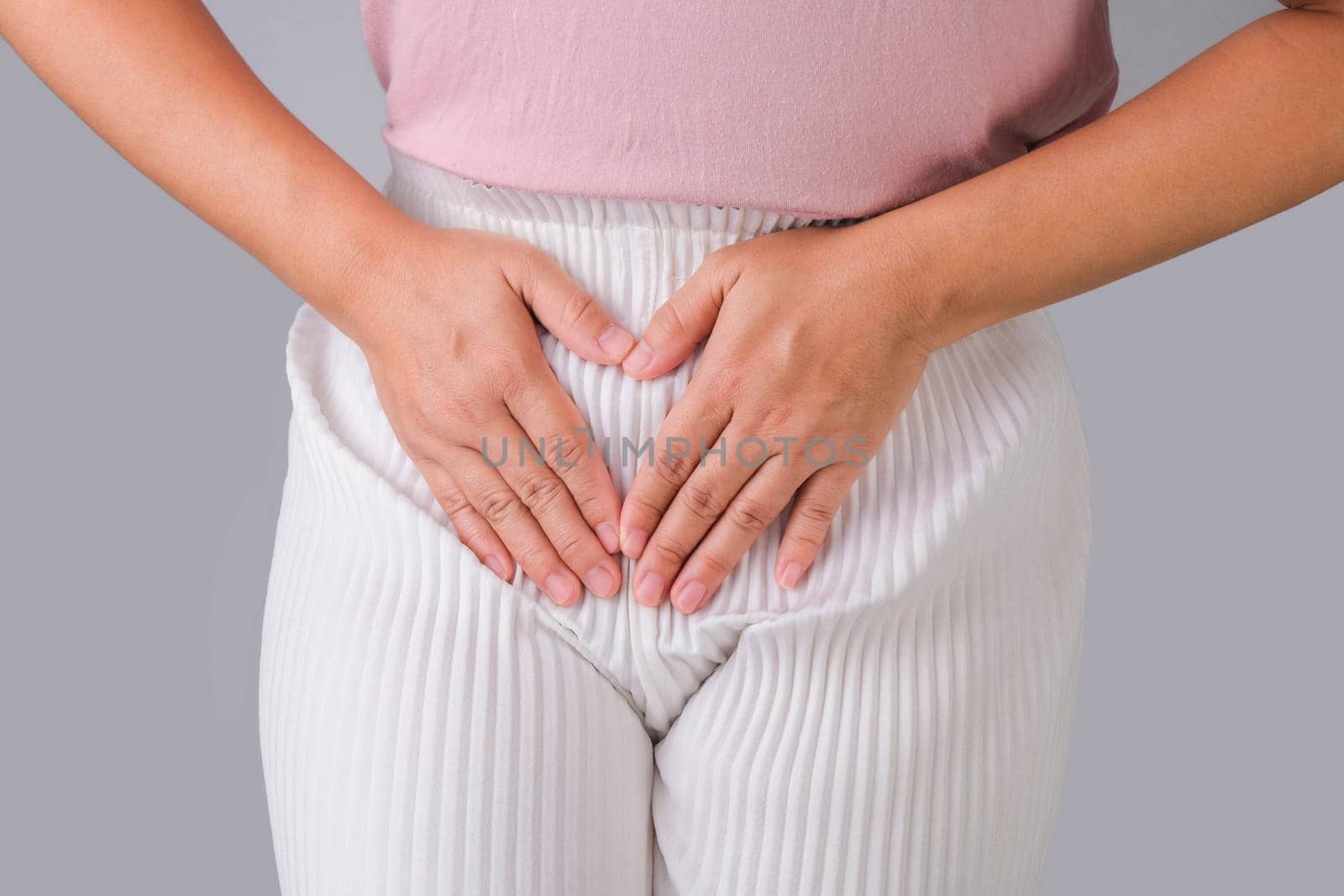 Woman with hands on her crotch isolated on white background. Female hand holding her crotch with pelvic pain or vaginal itching. gynecological problems. Health hygiene concept by TEERASAK