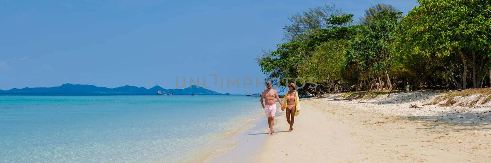 a couple of men and woman on the beach of Koh Kradan Island Thailand, men and women relaxing on the beach with a turqouse colored ocean