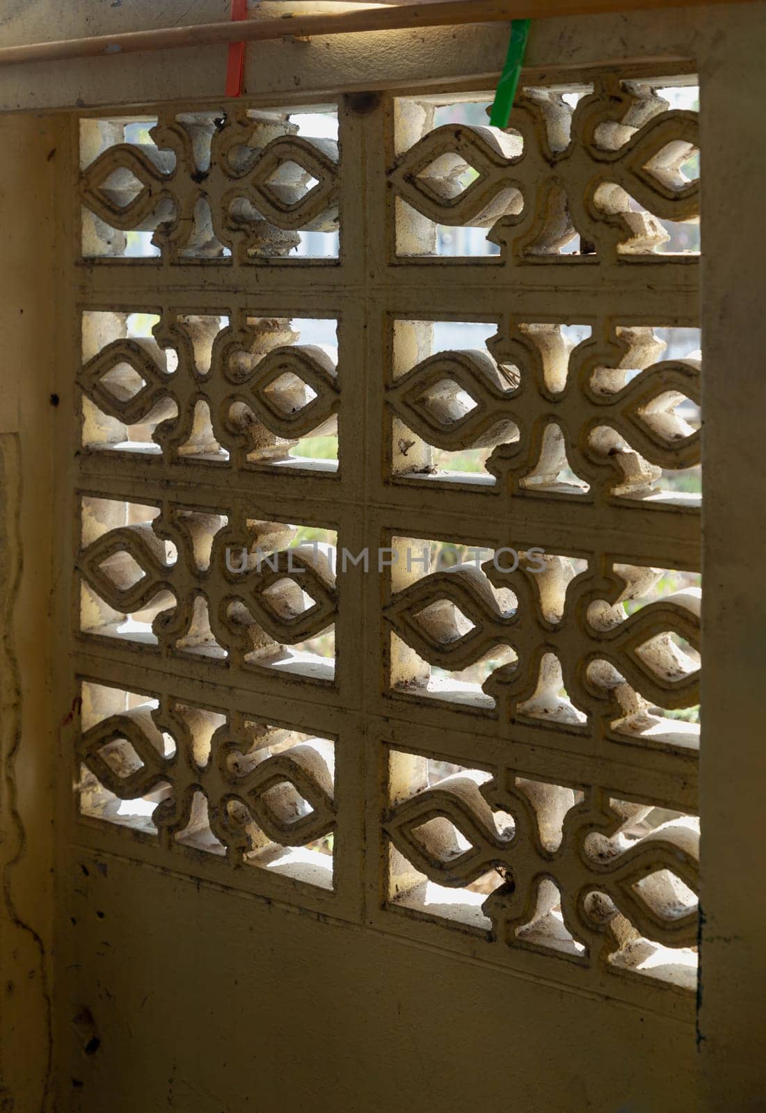The Sunlight is shining through the Decorative Old Hollow Concrete Blocks Wall or Old Breeze Blocks Wall. These Blocked Wall is a Concrete Wall that is designed with Various Patterns in Order to Allow the Air to flow freely through them. Geometric Architectural Concrete Cinder Blocks, Background or Wallpaper and texture. Unique design, Selective focus.