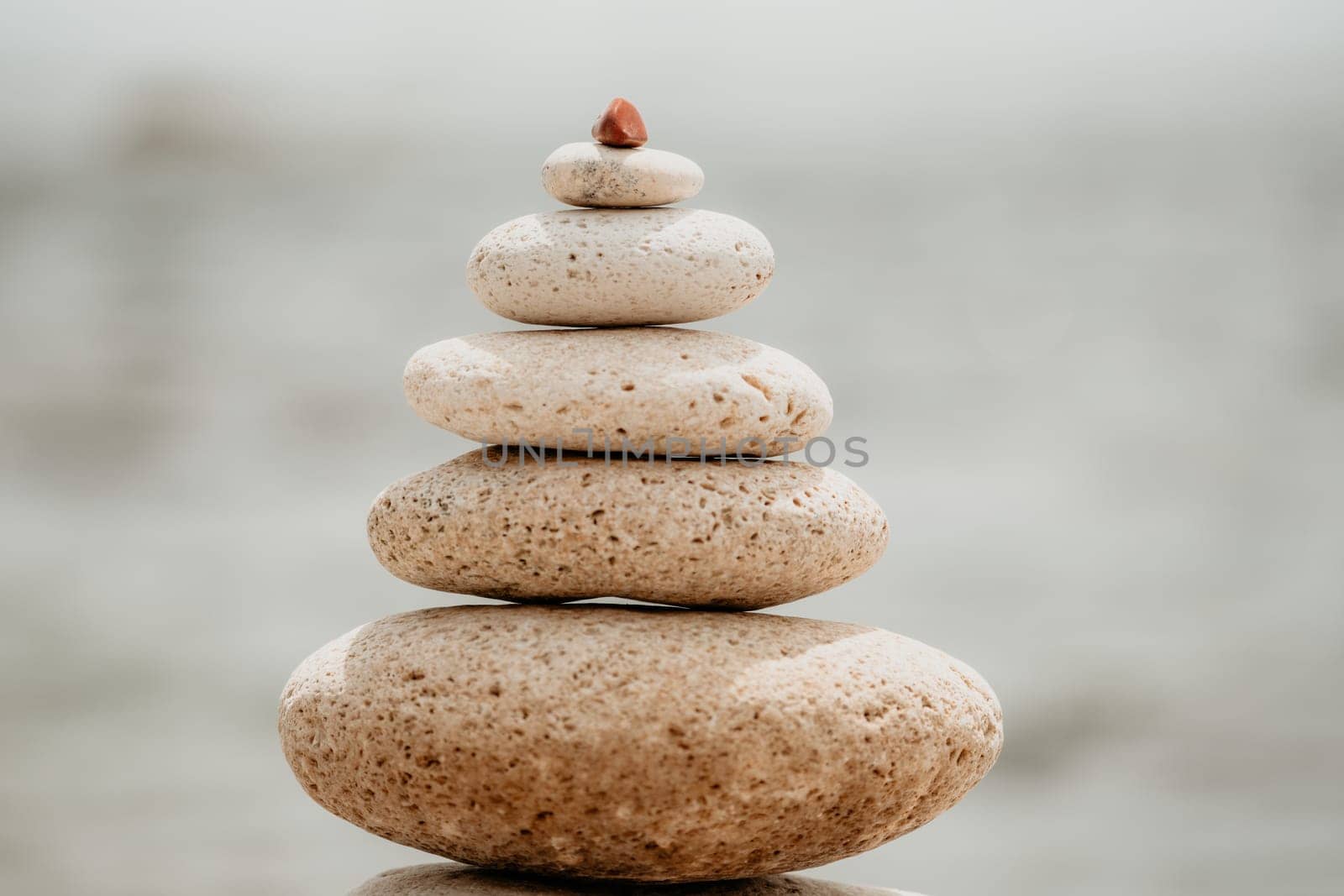 Pyramid stones on the seashore with warm sunset on the sea background. Happy holidays. Pebble beach, calm sea, travel destination. Concept of happy vacation on the sea, meditation, spa, calmness.