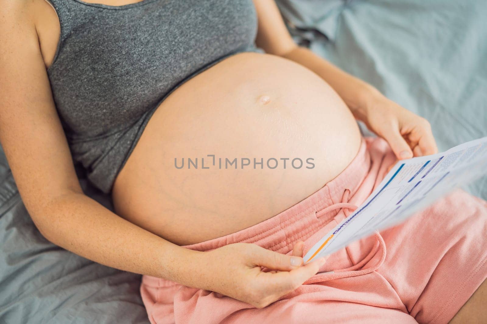 A pregnant woman looks at the results of a blood test printed on paper.
