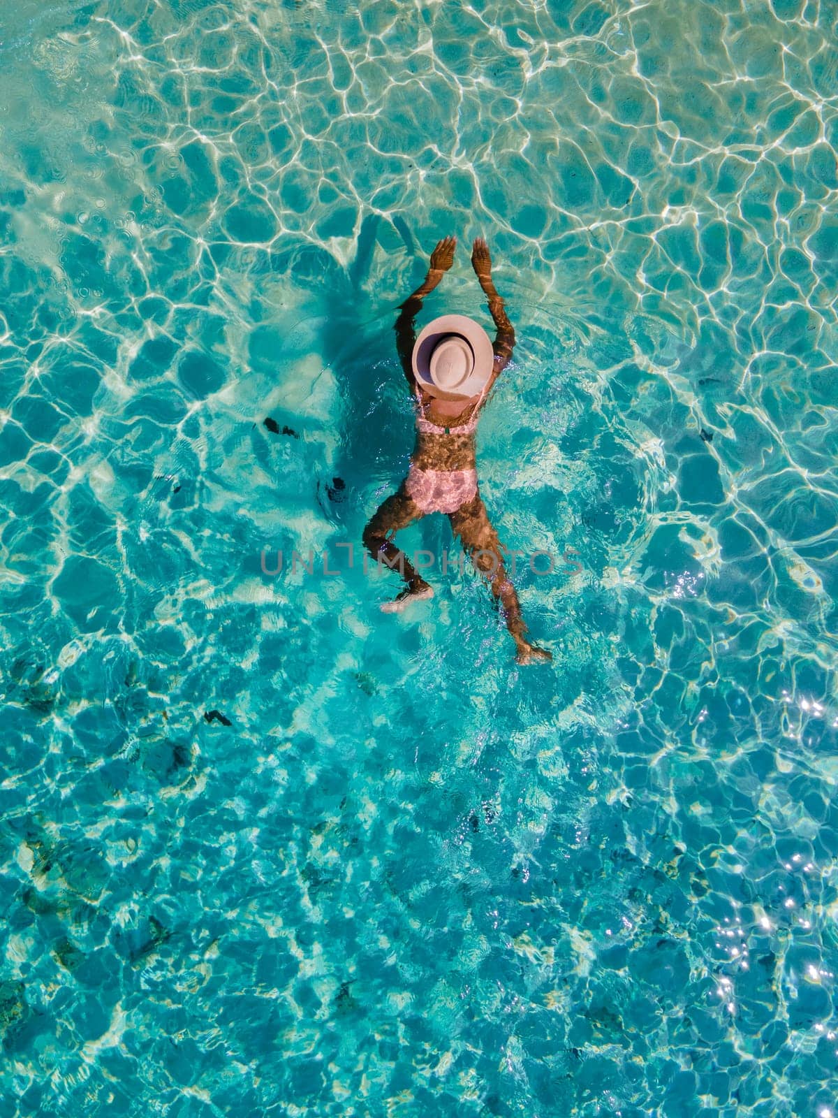 drone view of a woman swimming in the blue turqouse colored ocean of Koh Kradan island in Thailand
