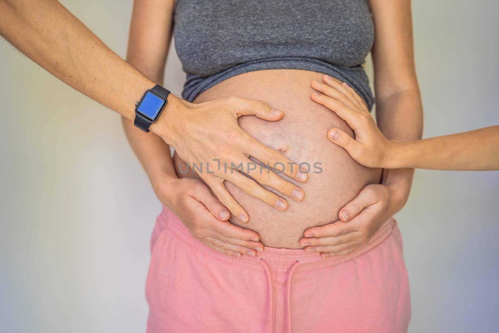 Mother's day, father's day, little cute blond boy touching mom's pregnant belly, husband holding his wife by the belly.