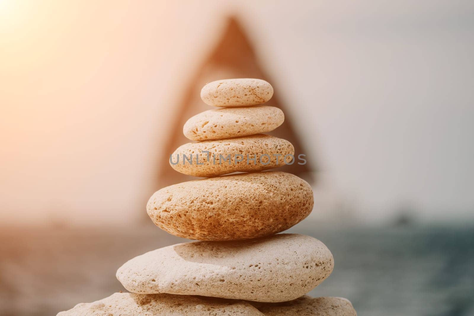 Pyramid stones on the seashore with warm sunset on the sea background. Happy holidays. Pebble beach, calm sea, travel destination. Concept of happy vacation on the sea, meditation, spa, calmness.