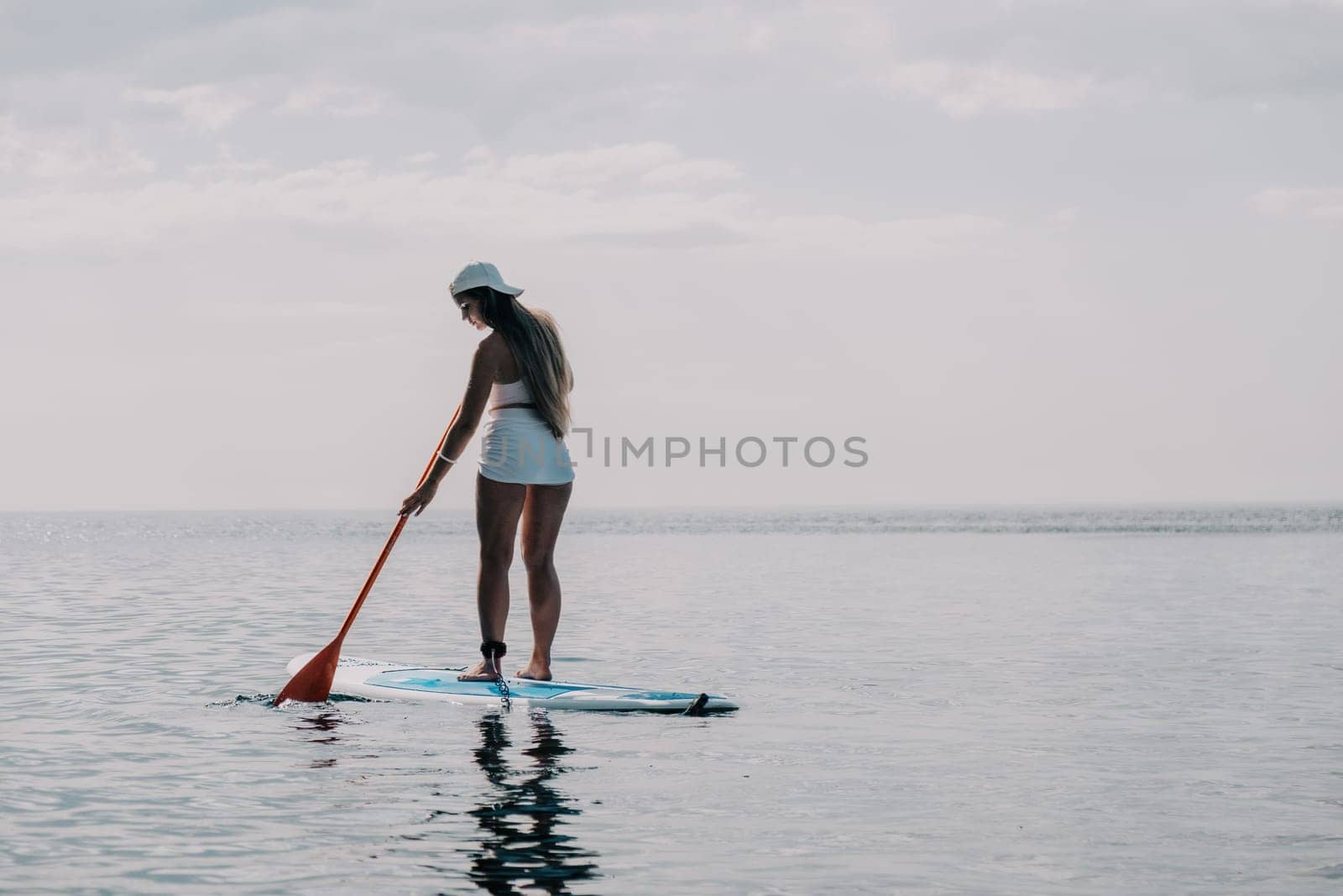 Woman sea sup. Close up portrait of happy young caucasian woman with long hair looking at camera and smiling. Cute woman portrait in bikini posing on sup board in the sea by panophotograph