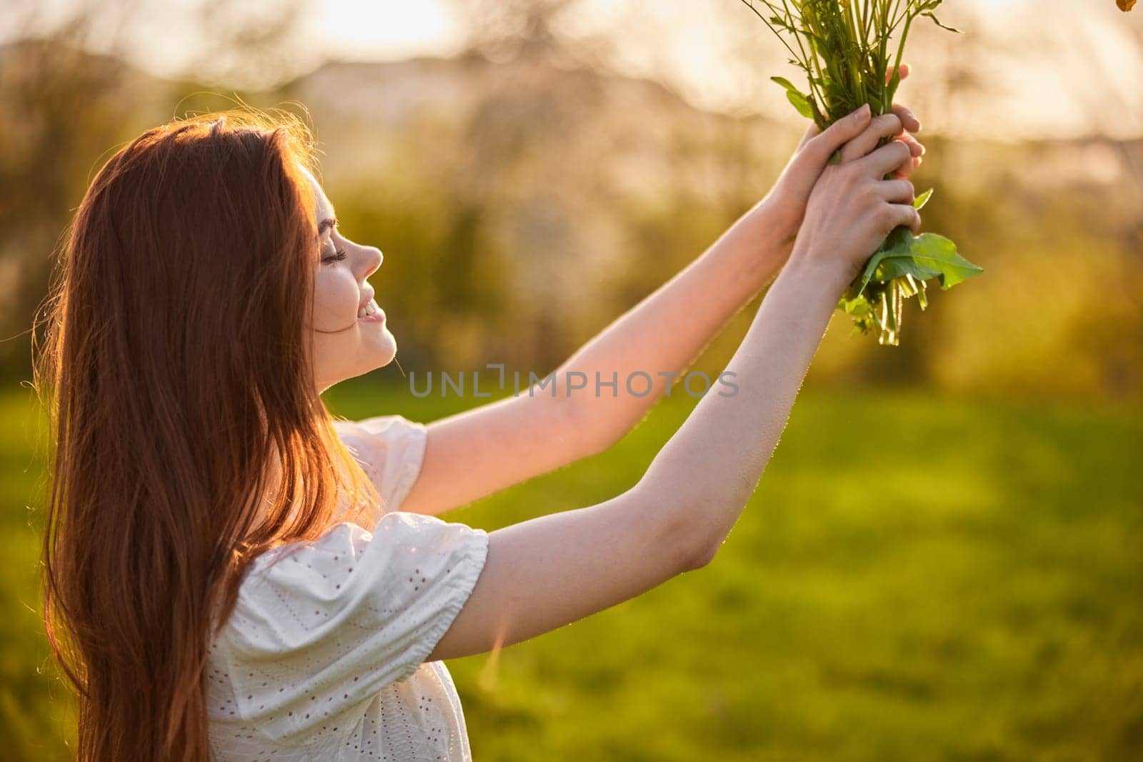 portrait of a woman standing sideways to the camera during sunset with a bouquet of wildflowers. High quality photo