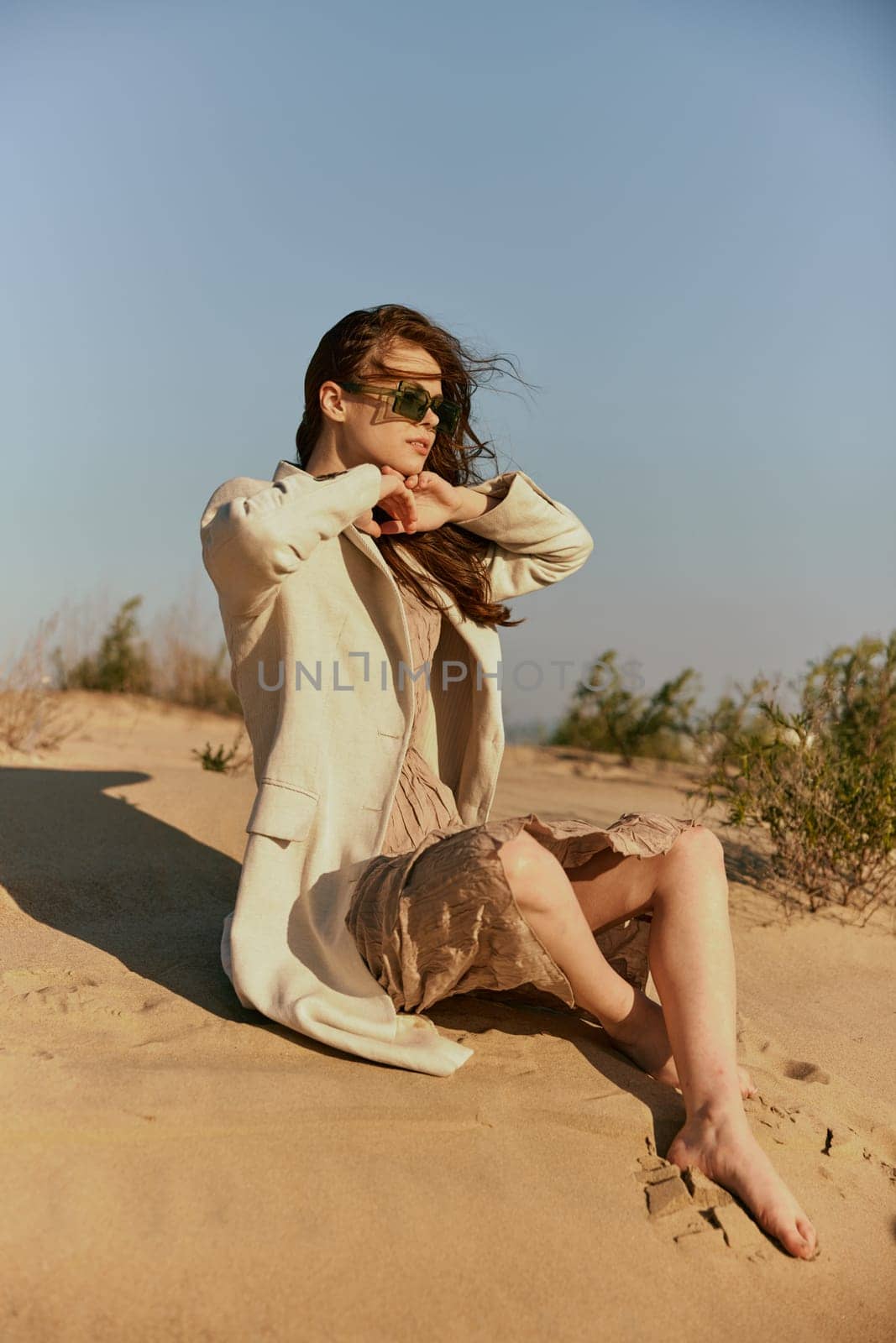 portrait of a beautiful stylish woman relaxing sitting on the sand near the sea. High quality photo