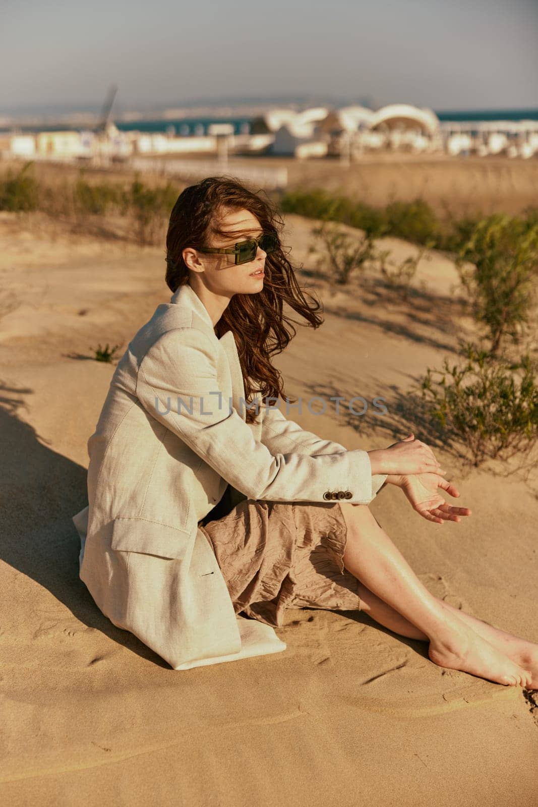 portrait of a beautiful stylish woman relaxing sitting on the sand near the sea. High quality photo