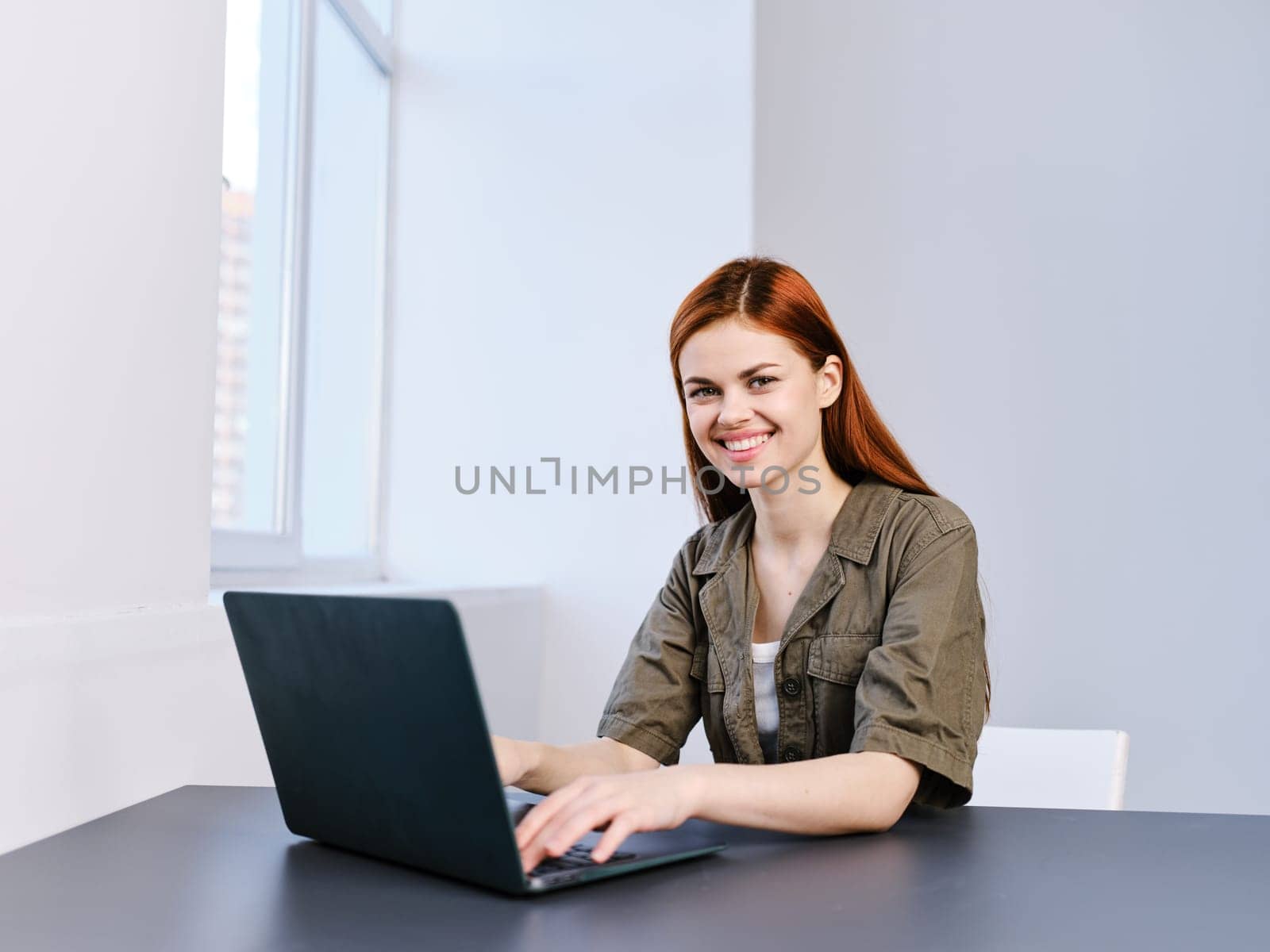 portrait of a happy woman at work with a laptop in a bright office. High quality photo