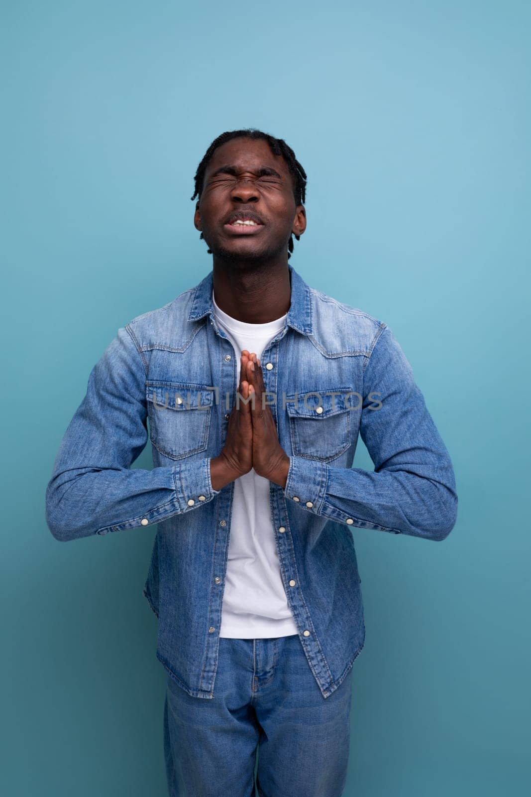 portrait of a young american man with dreadlocks in a denim jacket hoping and praying.