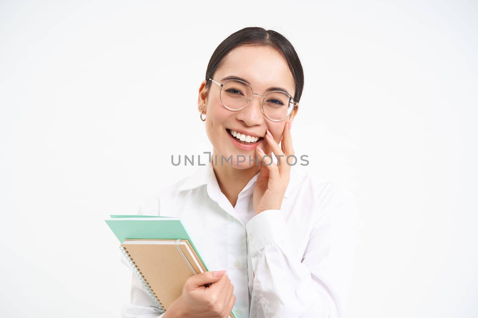 Successful young asian woman, teacher with notebooks, looking confident and smiling, white studio background.