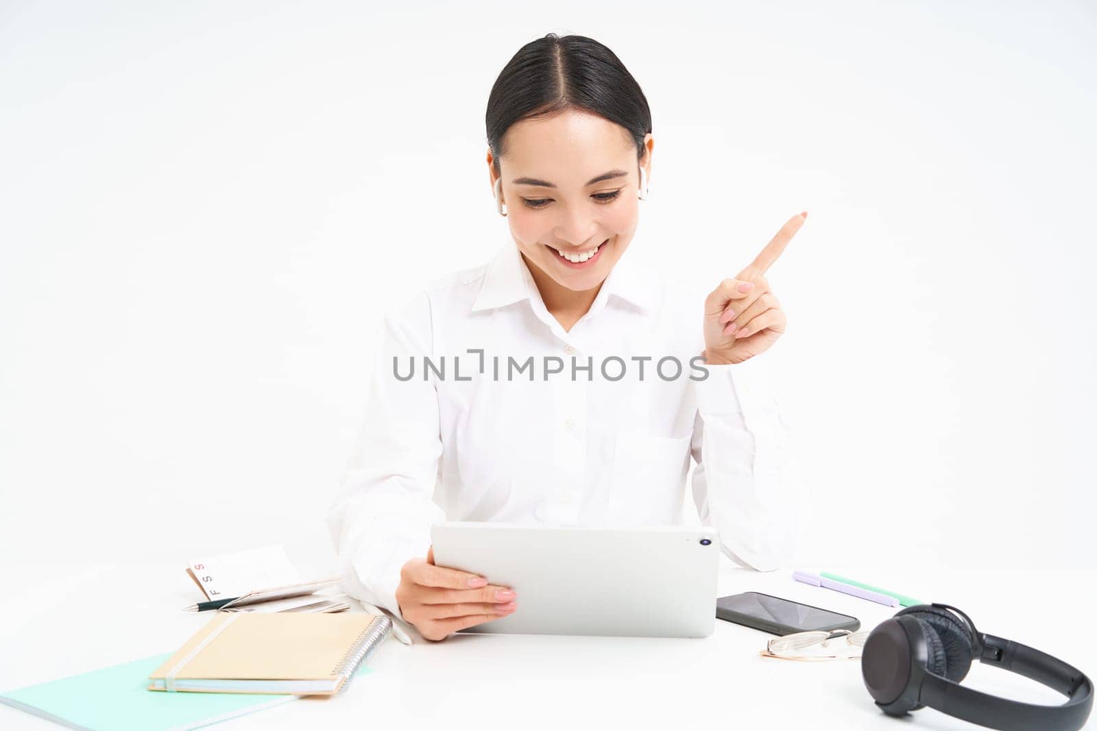 Portrait of successful female employee, asian woman talks via digital tablet on video chat, has online meeting with client while sits in her office, white background.