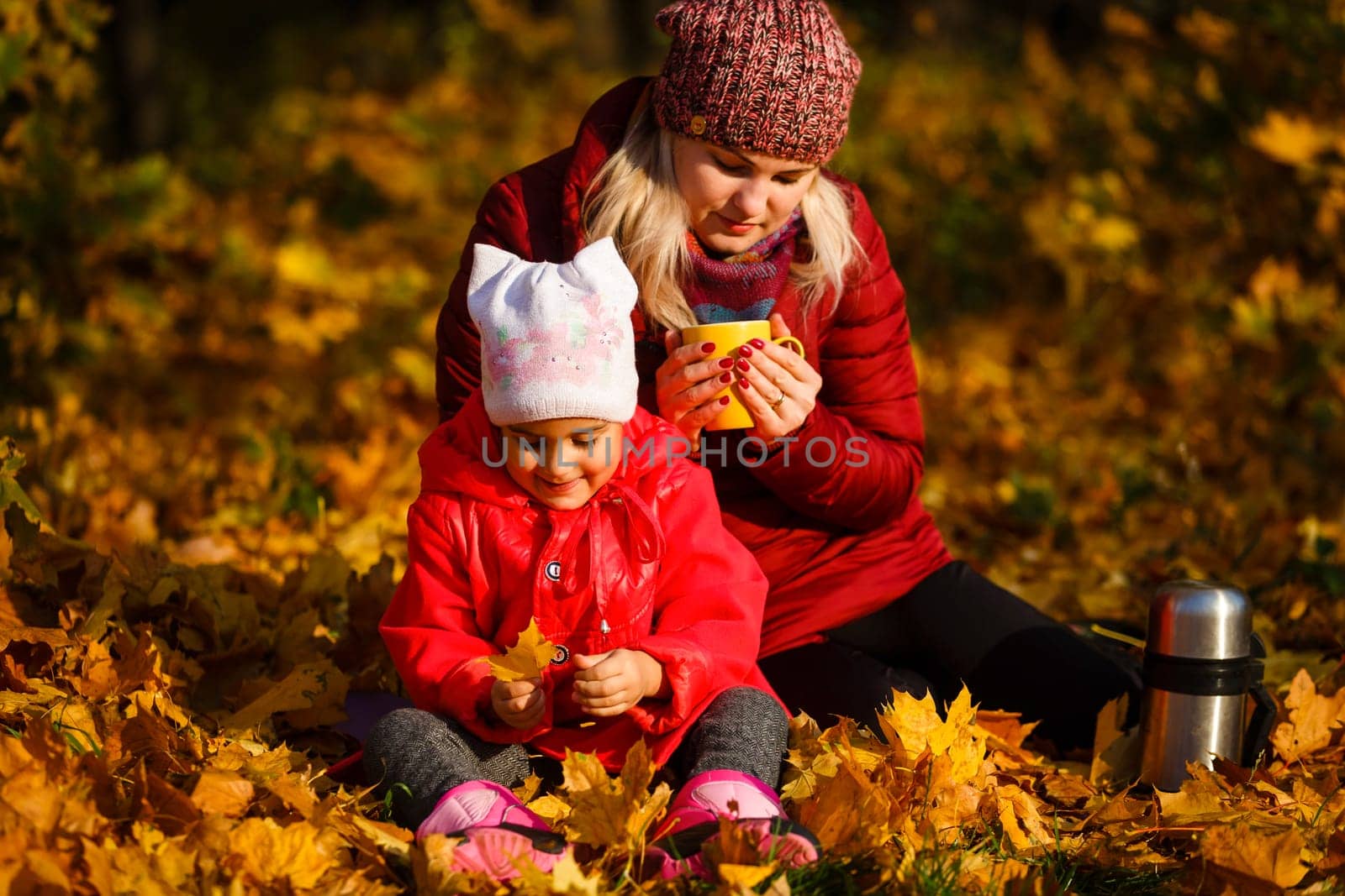 Hello autumn. smiling young mother and daughter in hats outdoors in the city park in autumn having fun time. by Andelov13