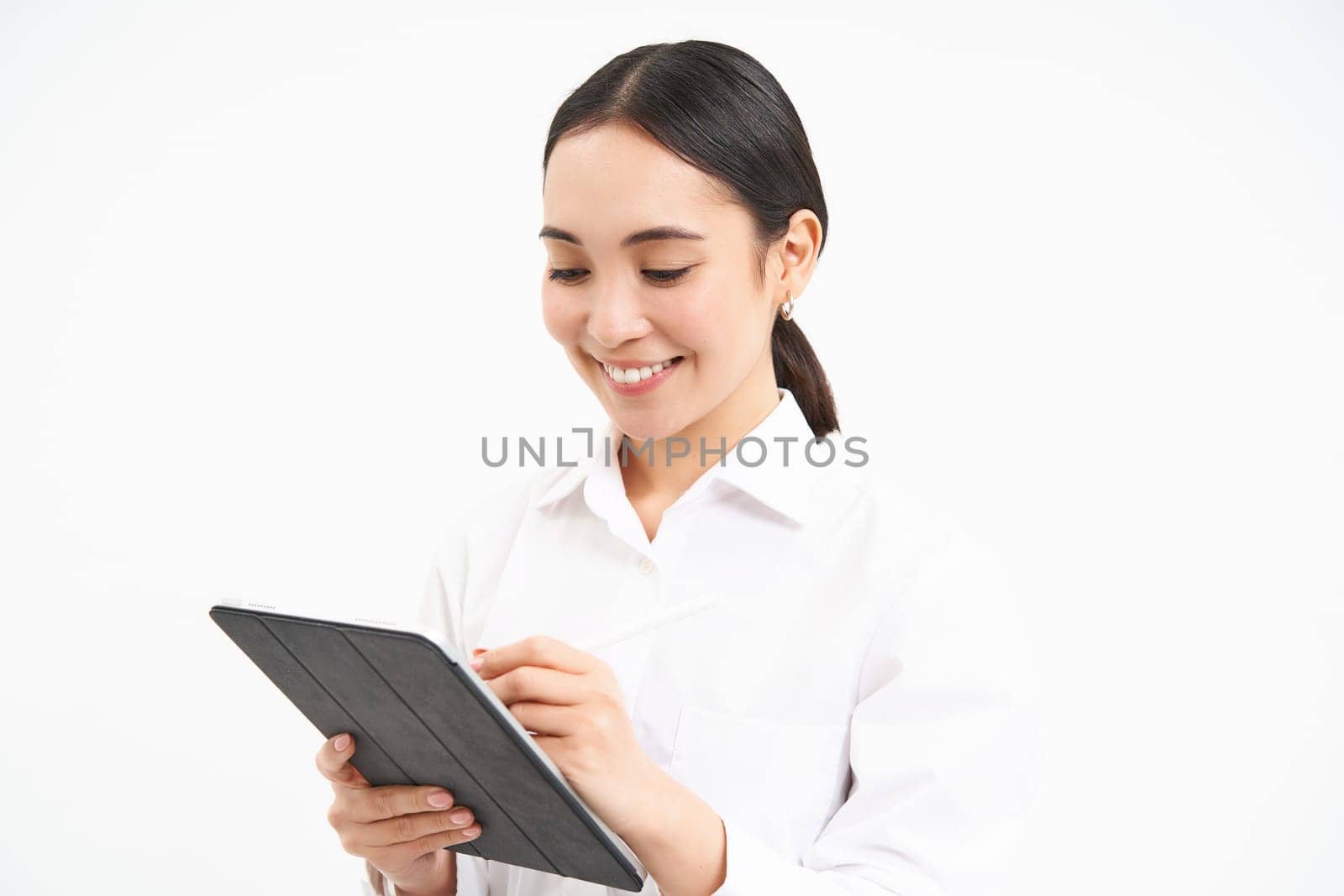 Portrait of businesswoman working on digital tablet, creating diagrams for meeting conference on gadget, standing over white background.