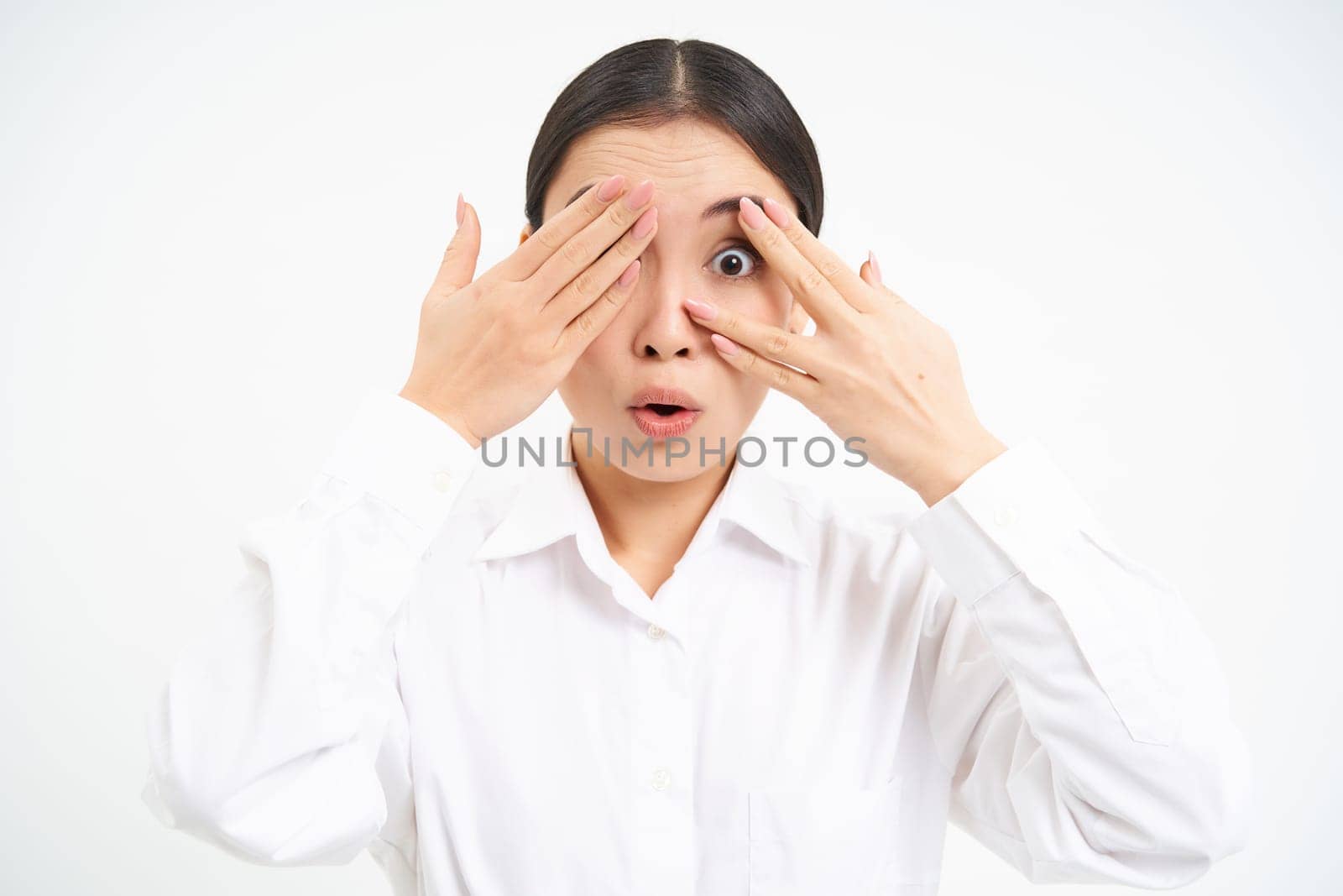 Asian woman entrepreneur, businesswoman shuts her eyes with hands, stands blindfolded against white studio background by Benzoix