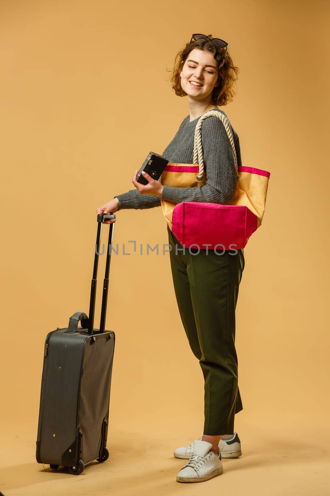 concept of travel. happy woman girl with suitcase and passport on yellow colored background. by Andelov13
