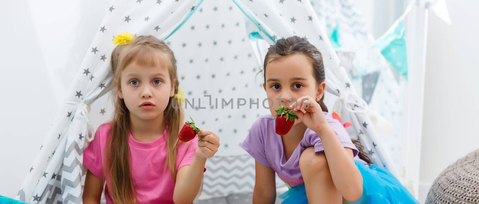 Two little cute girls sitting and eating strawberries. by Andelov13