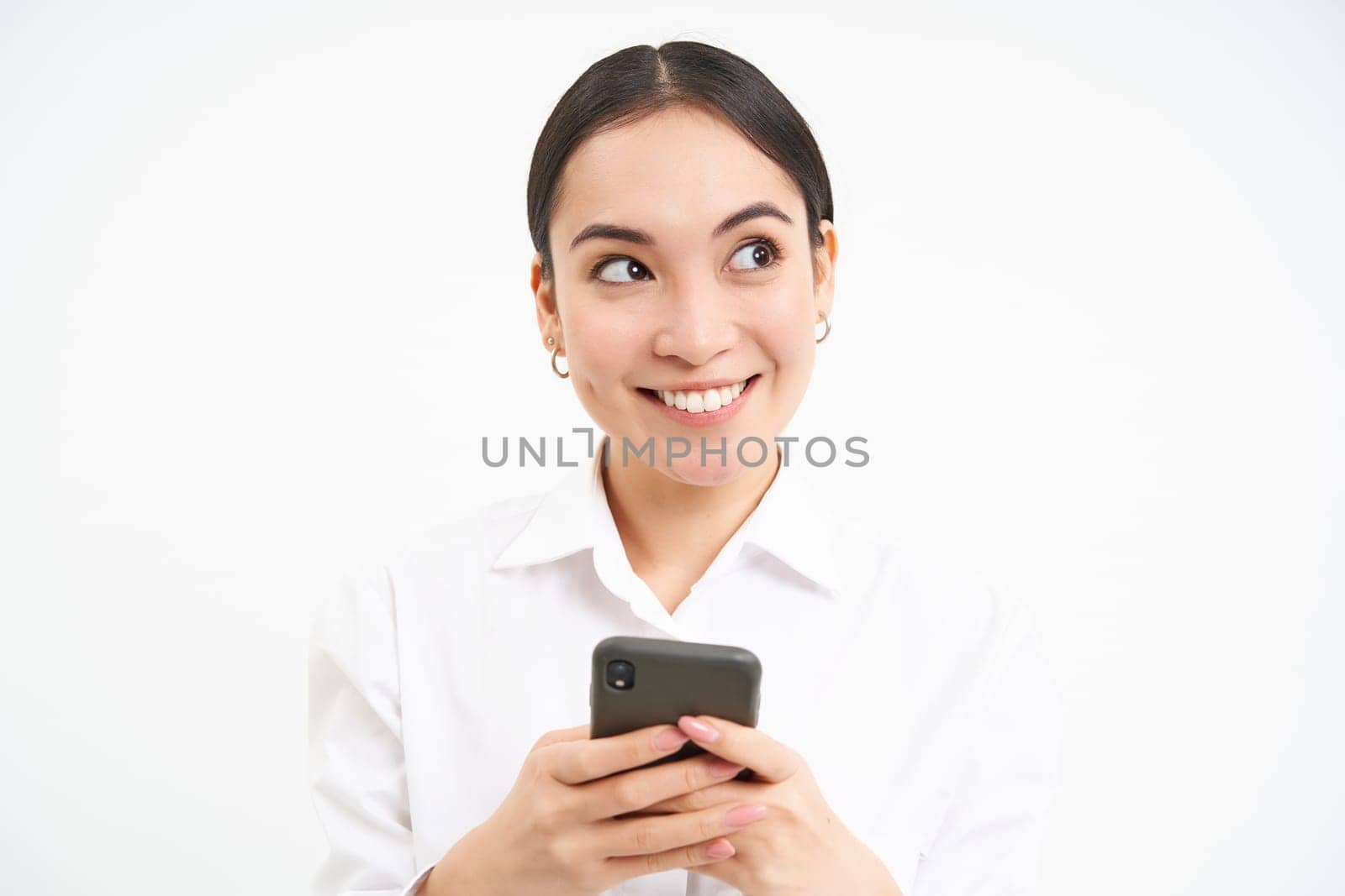 Image of asian saleswoman, office manager holding smartphone, working on text for social media, using cellphone, white background by Benzoix