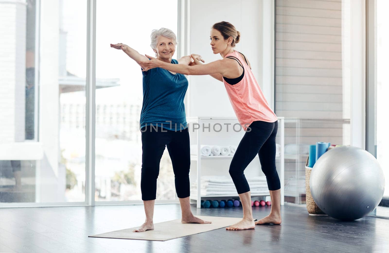 Yoga accommodates all ages. a fitness instructor helping a senior woman during a yoga class. by YuriArcurs