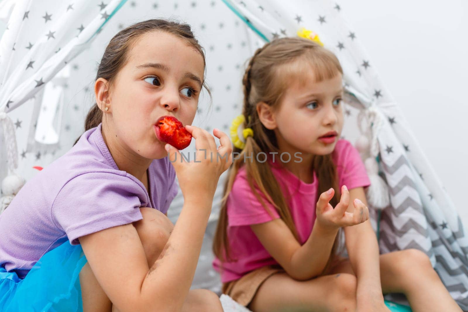 two little girls eating strawberries.