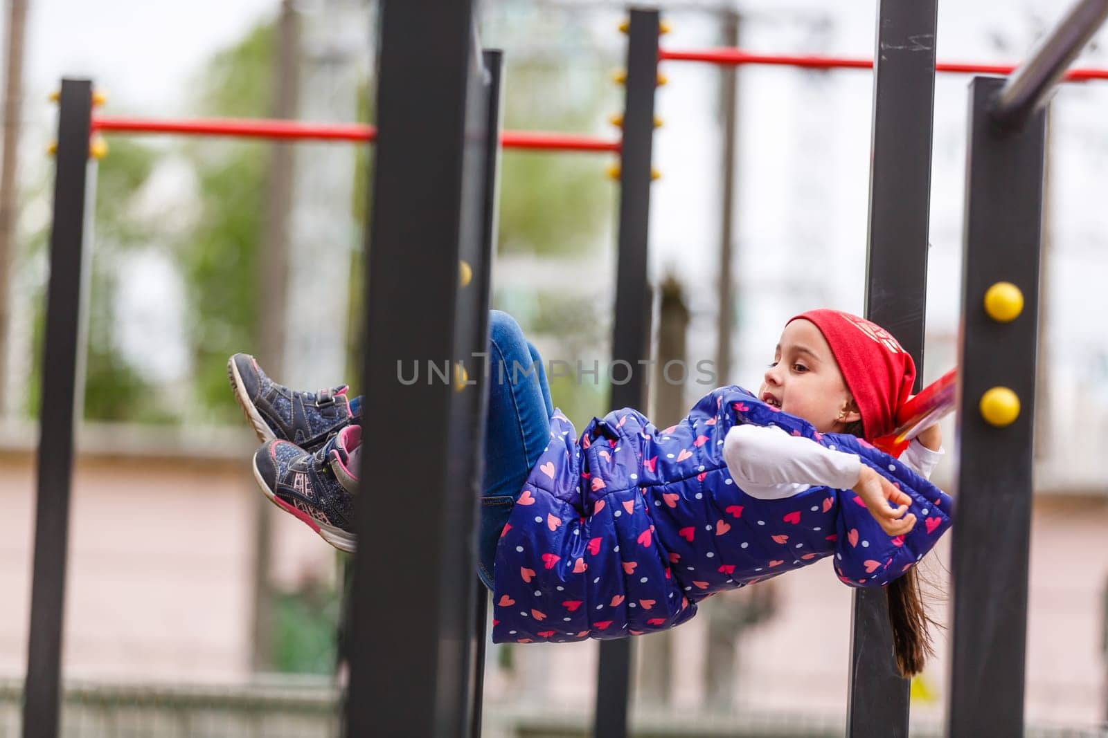 Active little girl playing on a playground by Andelov13