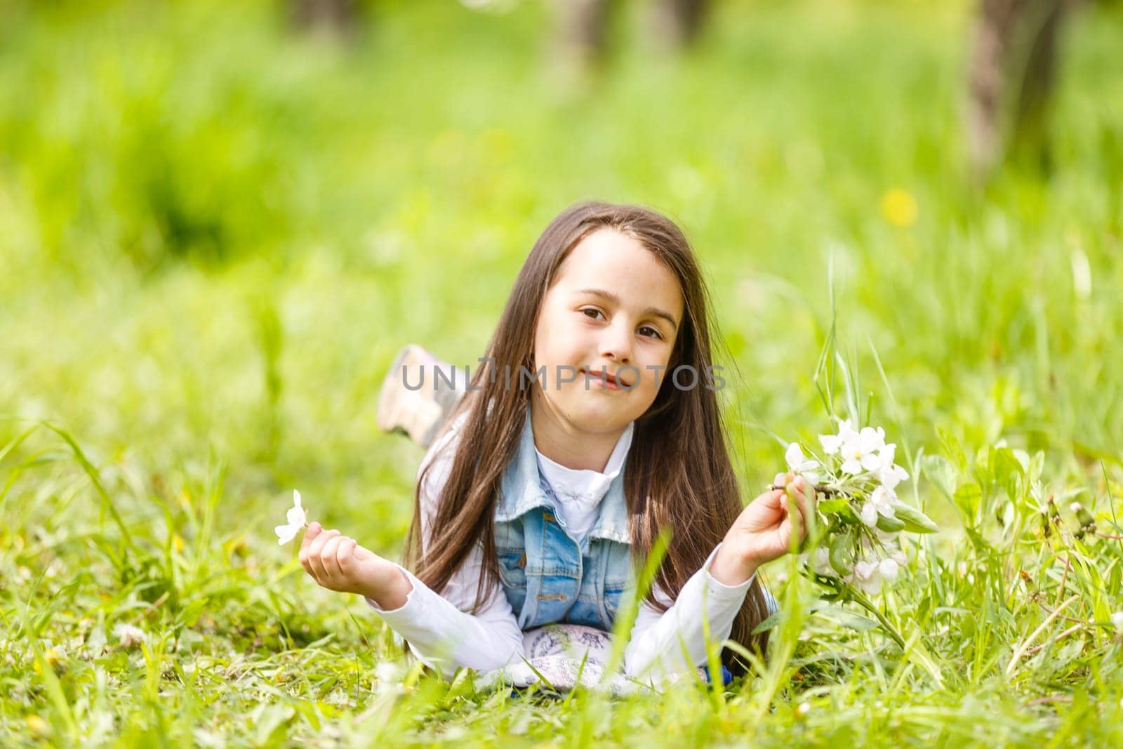Portrait of a smiling little girl lying on green grass.