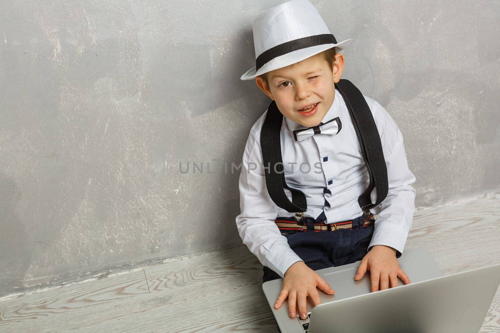 Young man sits on the laminate floor with black laptop. Top view