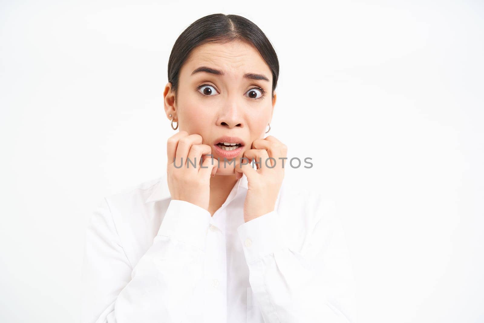 Portrait of asian businesswoman looks scared, stares terrified and anxious, trembling from fear, stands over white background.