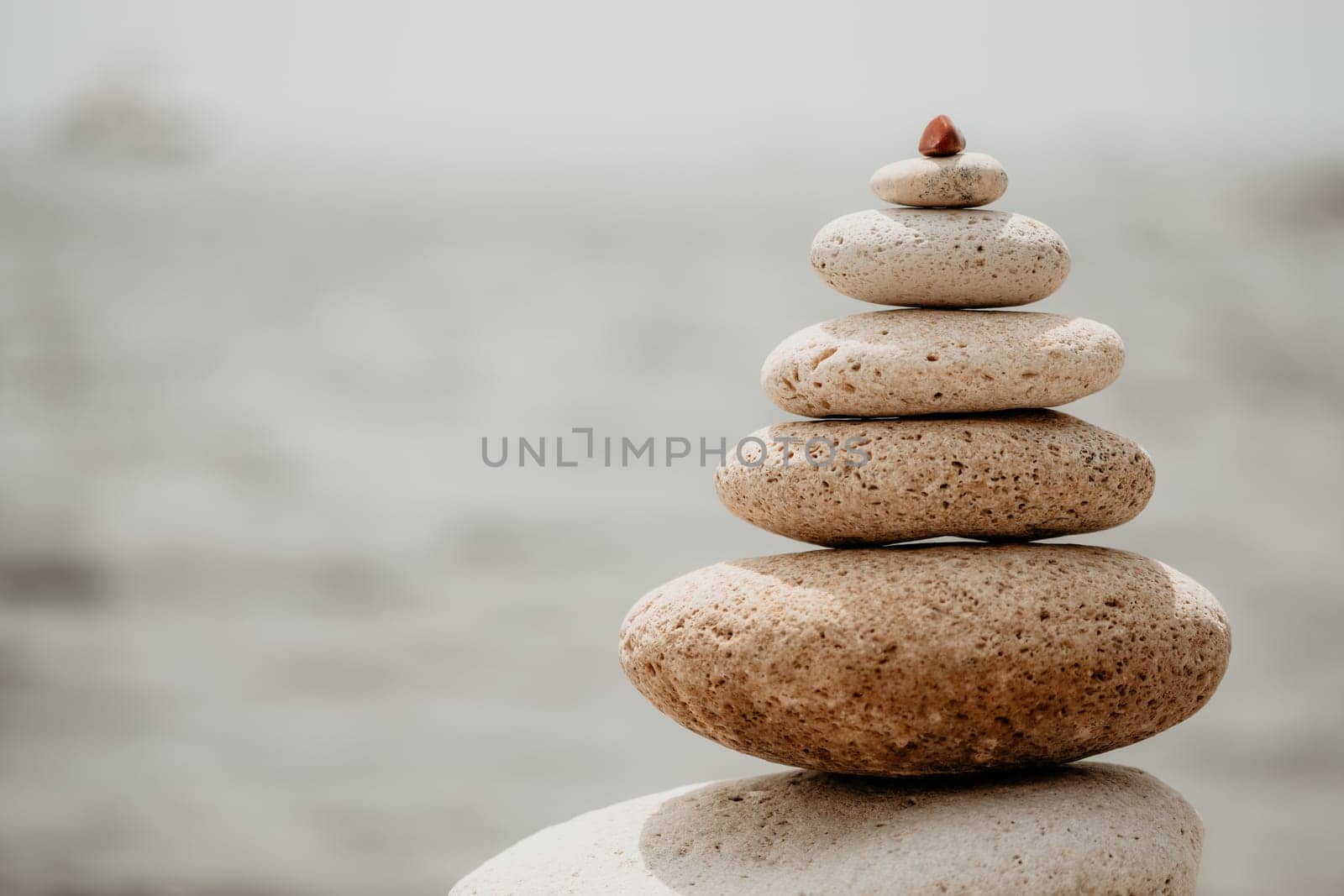 Pyramid stones on seashore with warm sunset on sea background for perfect holiday. Pebble beach and calm sea create a serene travel destination. concepts of happy vacation, meditation spa and calmness by panophotograph
