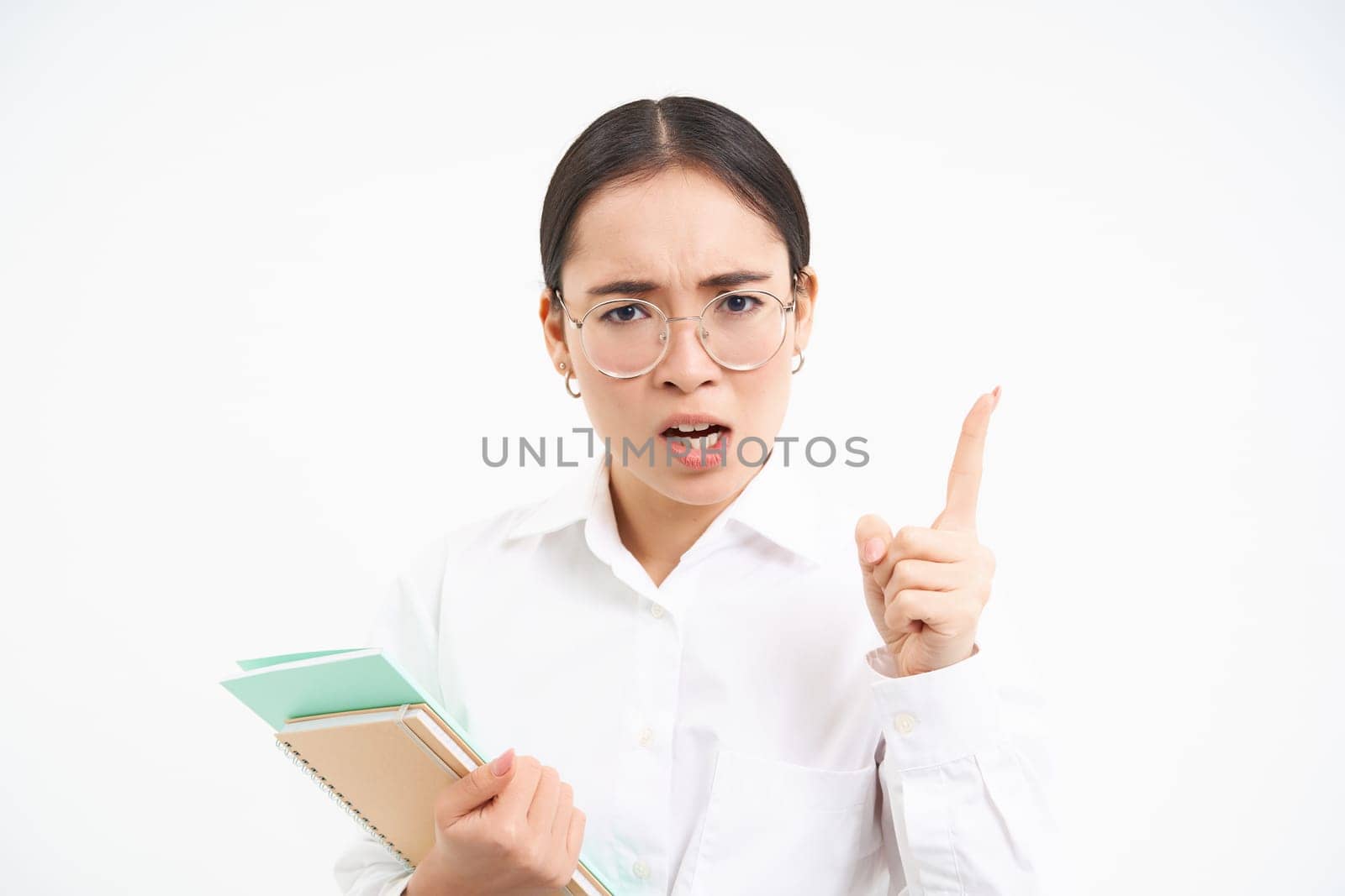 Disappointed, serious japanese teacher, woman shakes finger in disapproval, scolding student, standing over white background.