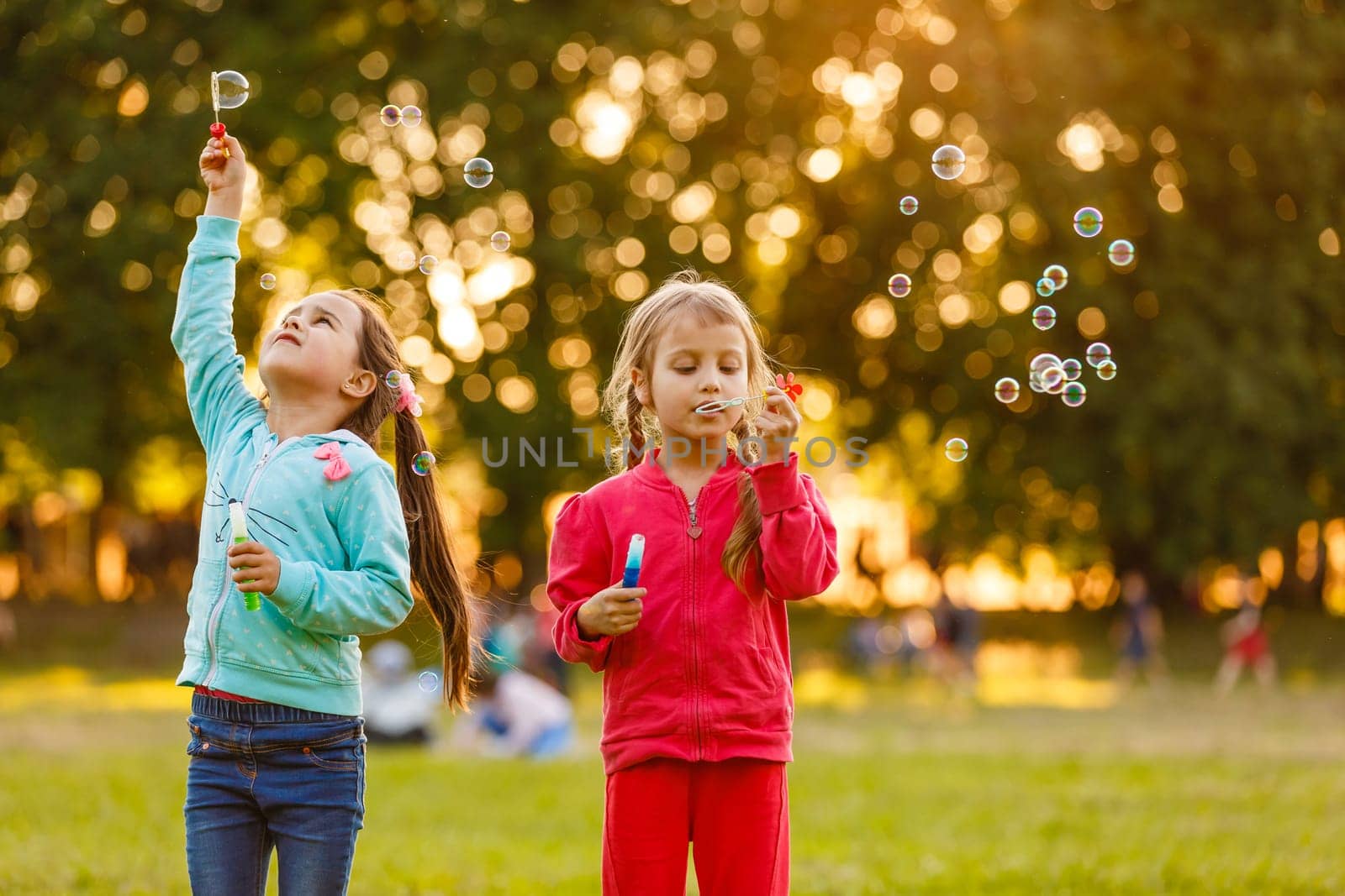 Two young Caucasian girls blowing bubbles.