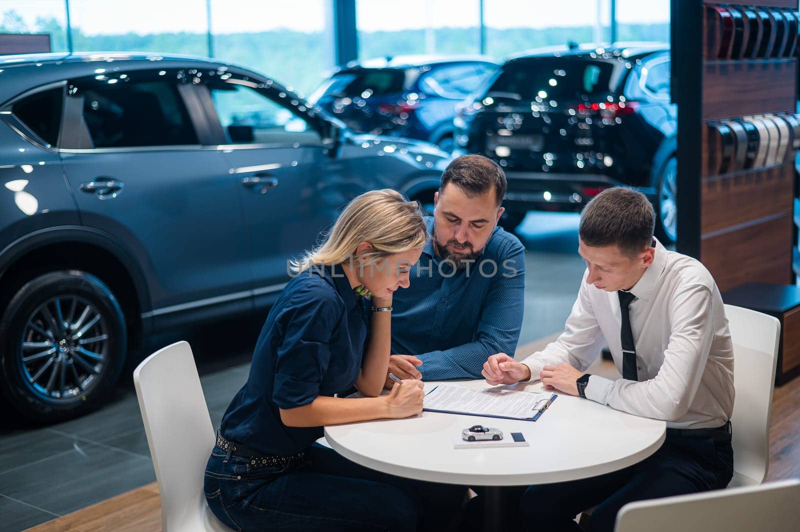 Happy caucasian couple signs a contract for the purchase of a car salon