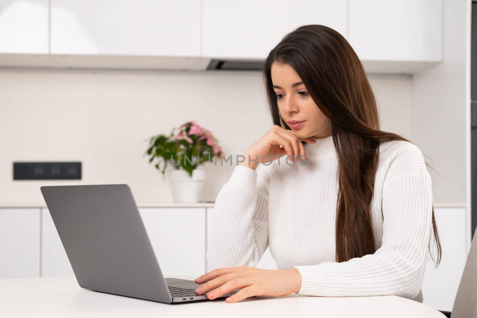Exhausted young woman working at home using laptop.