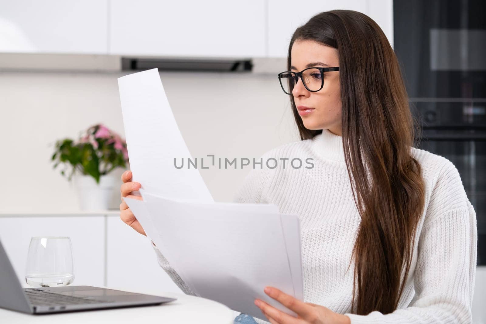 Cheerful lady holding paper uses a computer and works remotely. Distance freelance job concept.