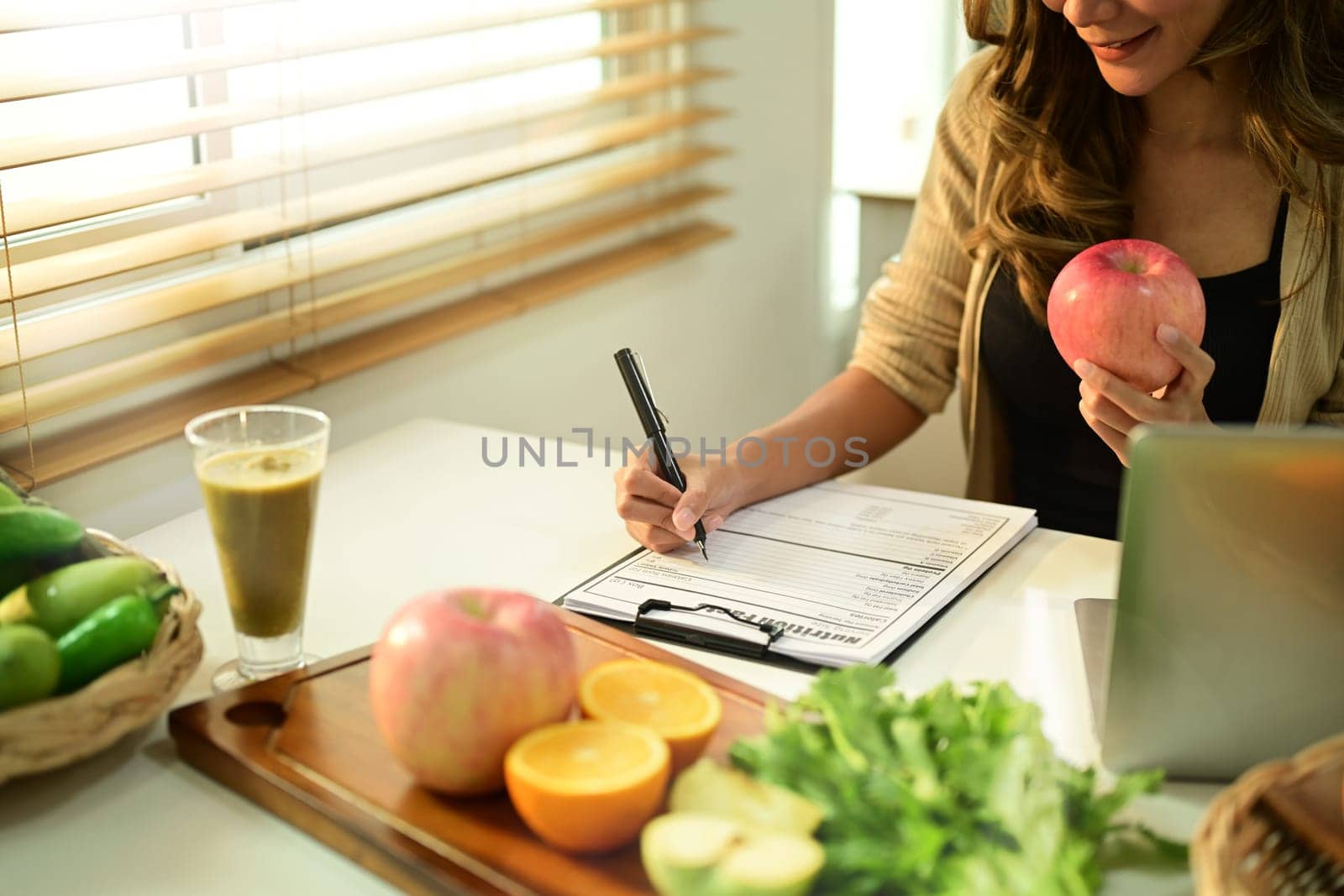 Nutritionist sitting at desk with fruit and vegetable, working on diet plan. Healthy eating, right nutrition and diet concept by prathanchorruangsak
