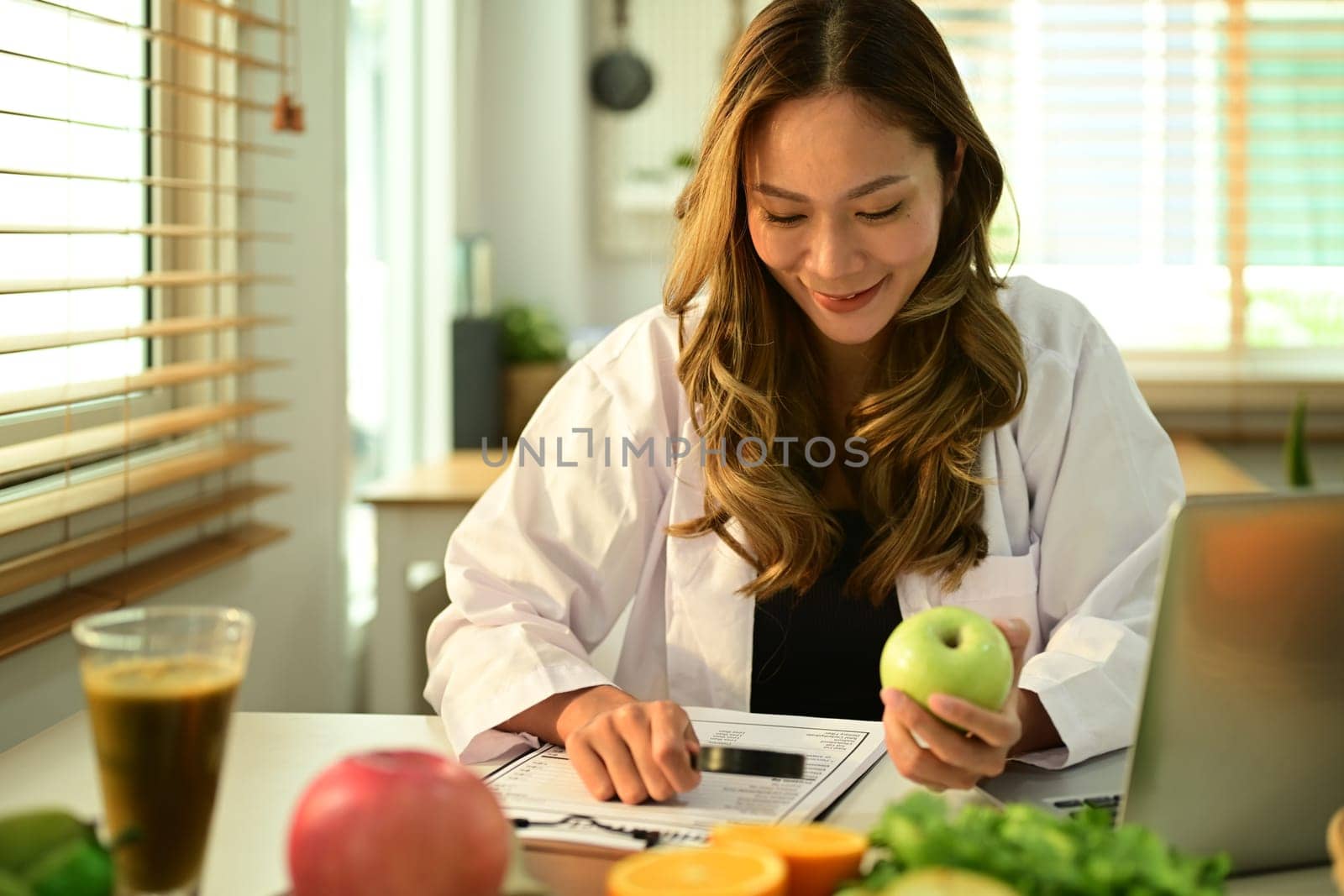 Professional nutritionist working on a diet plan, sitting with different healthy food ingredients in office. Right nutrition, healthy eating.